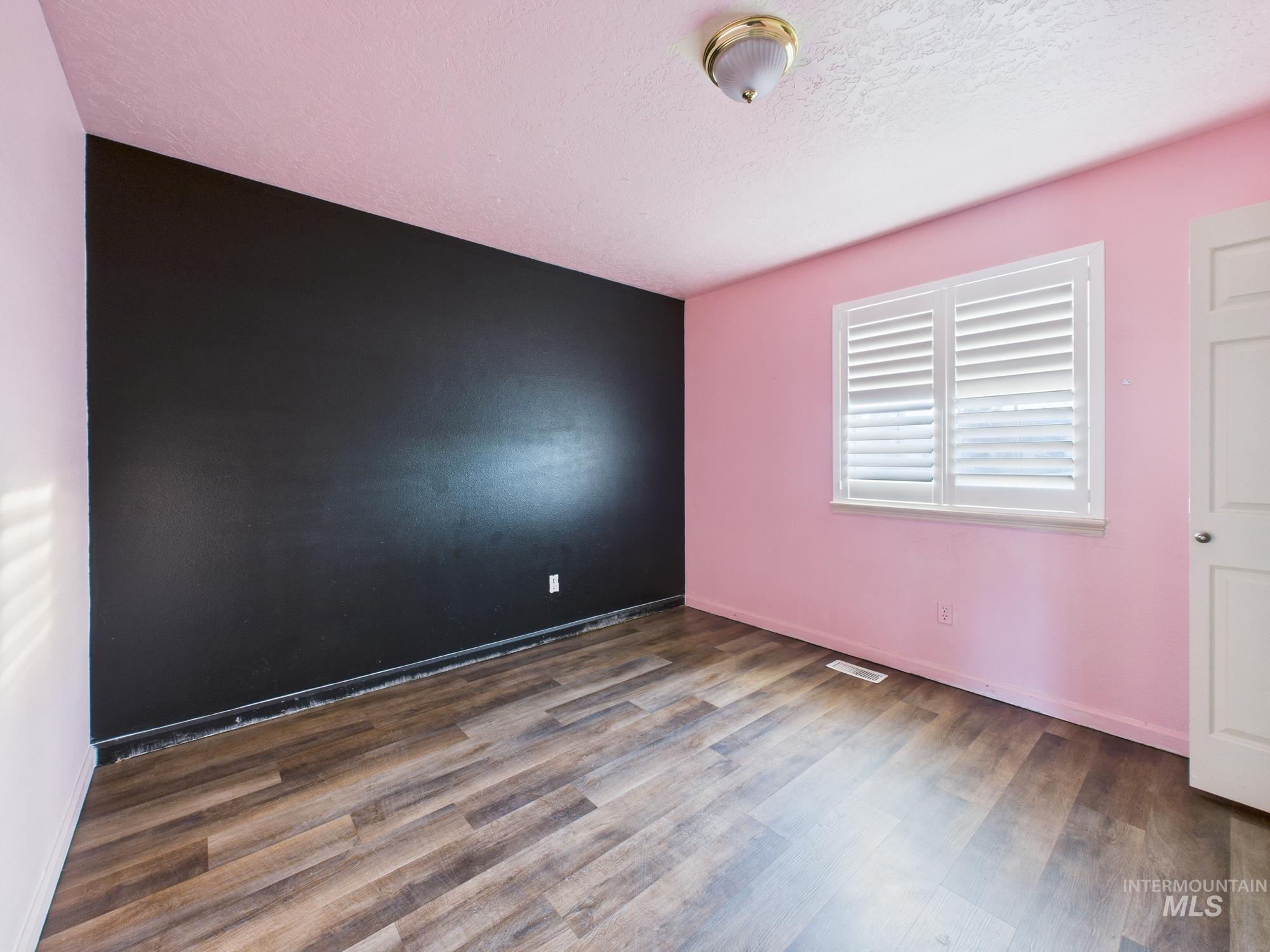 Unfurnished room featuring wood finished floors and a textured ceiling
