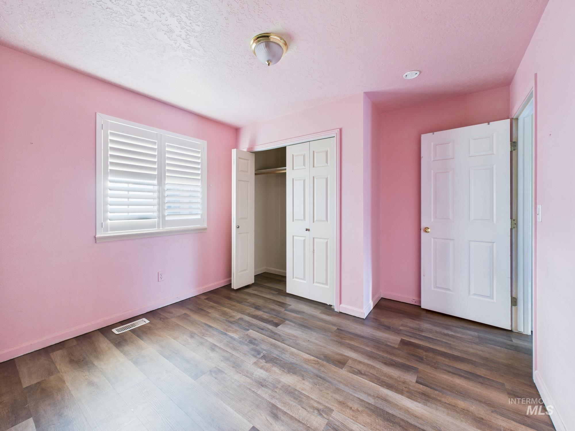 Unfurnished bedroom featuring a closet, a textured ceiling, and dark wood-style floors