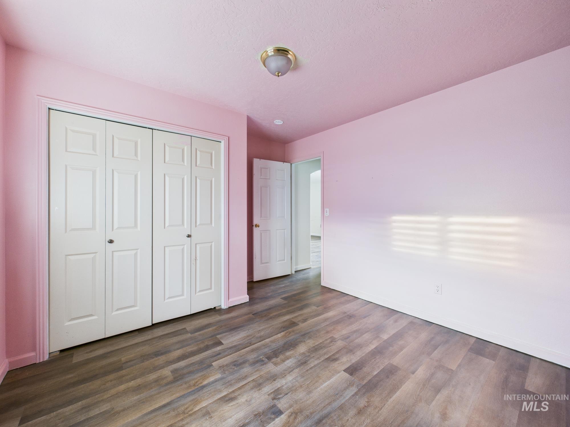 Unfurnished bedroom featuring dark wood-style flooring and a closet