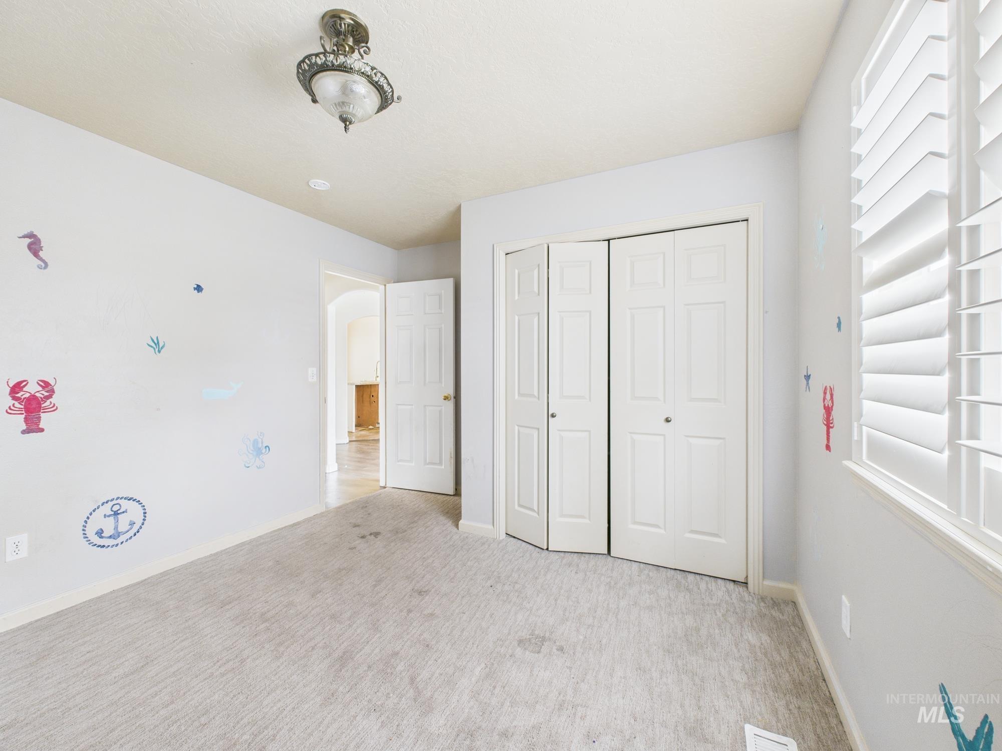 Unfurnished bedroom featuring carpet floors, arched walkways, and a closet