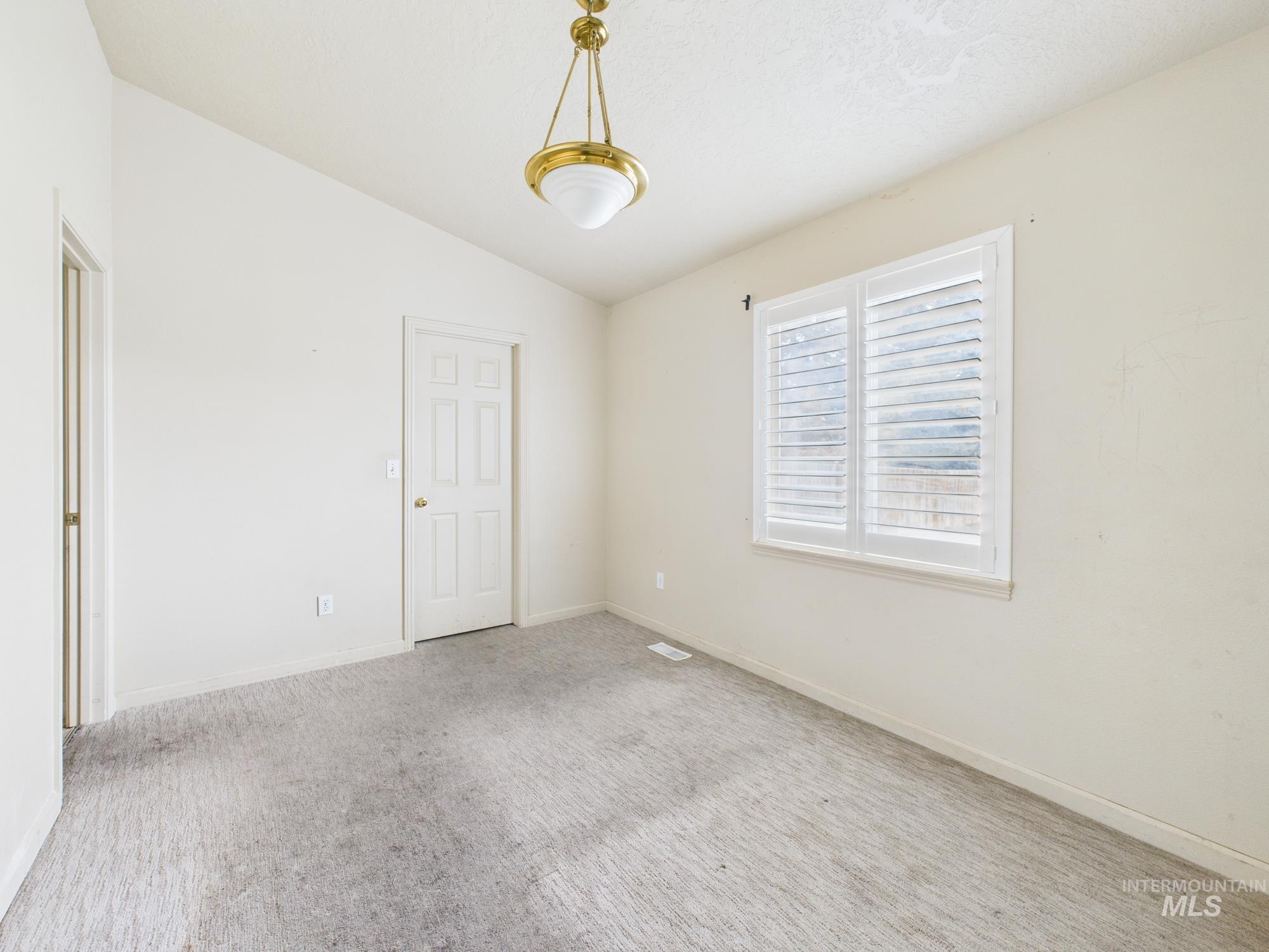 Spare room featuring vaulted ceiling and carpet floors