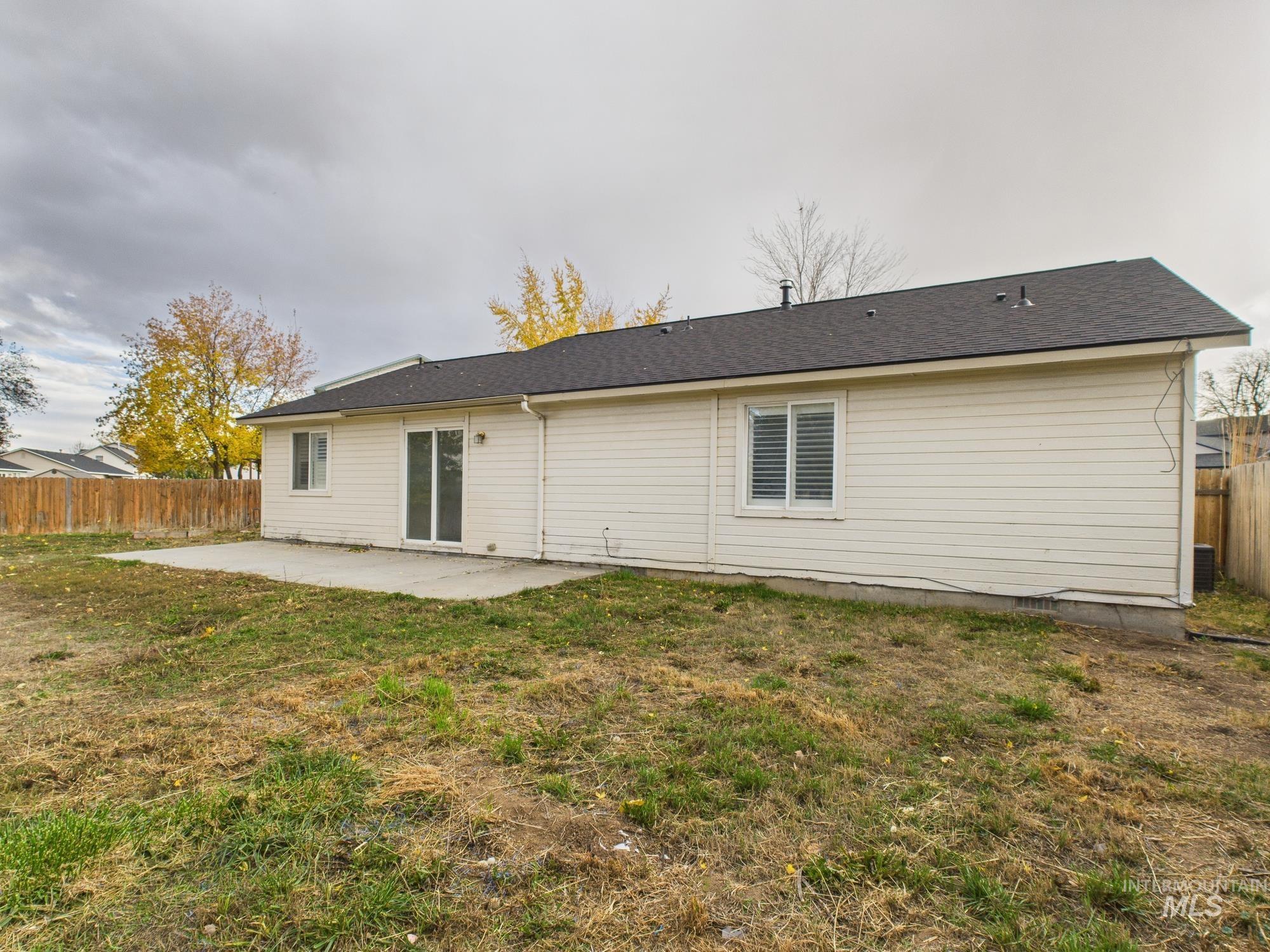 Rear view of property with a fenced backyard, a patio area, and a shingled roof