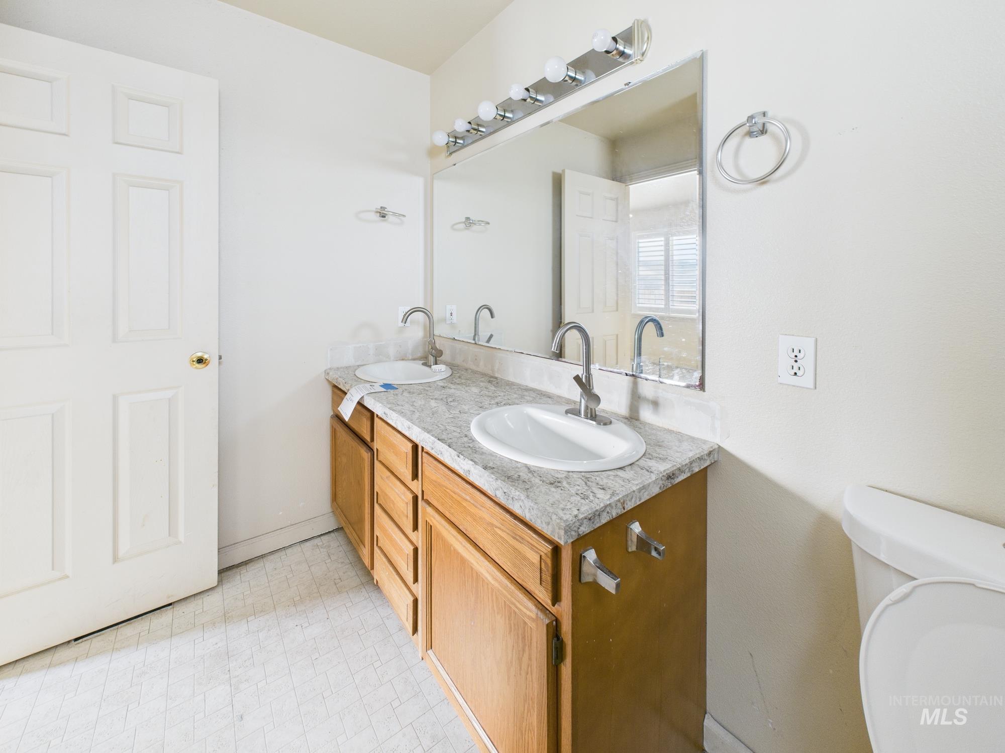Full bath featuring double vanity and toilet