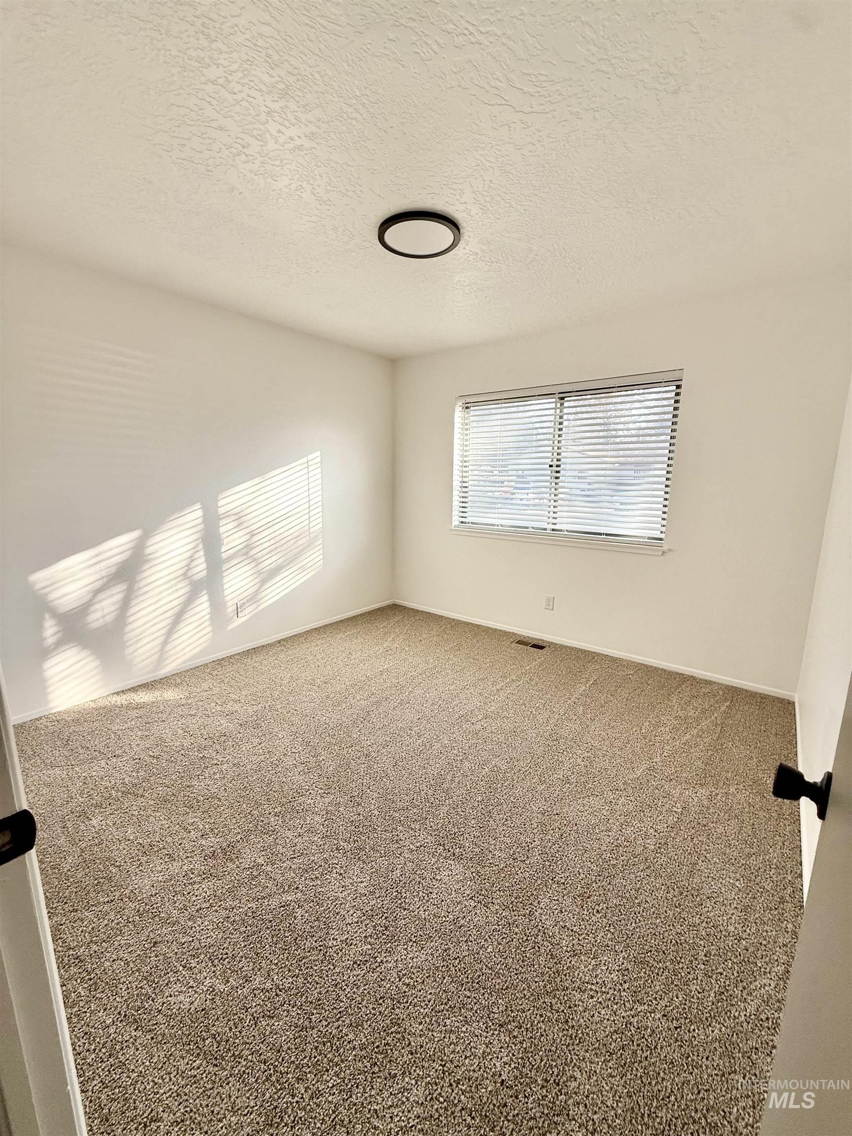 Unfurnished room featuring carpet and a textured ceiling