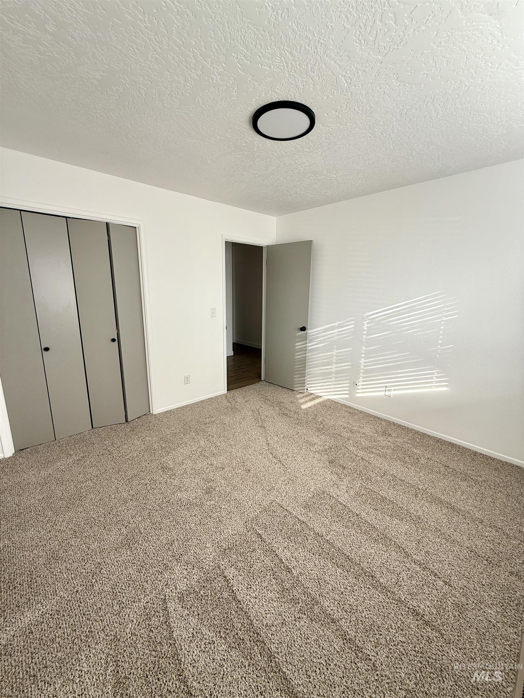 Unfurnished bedroom with a closet, carpet floors, and a textured ceiling