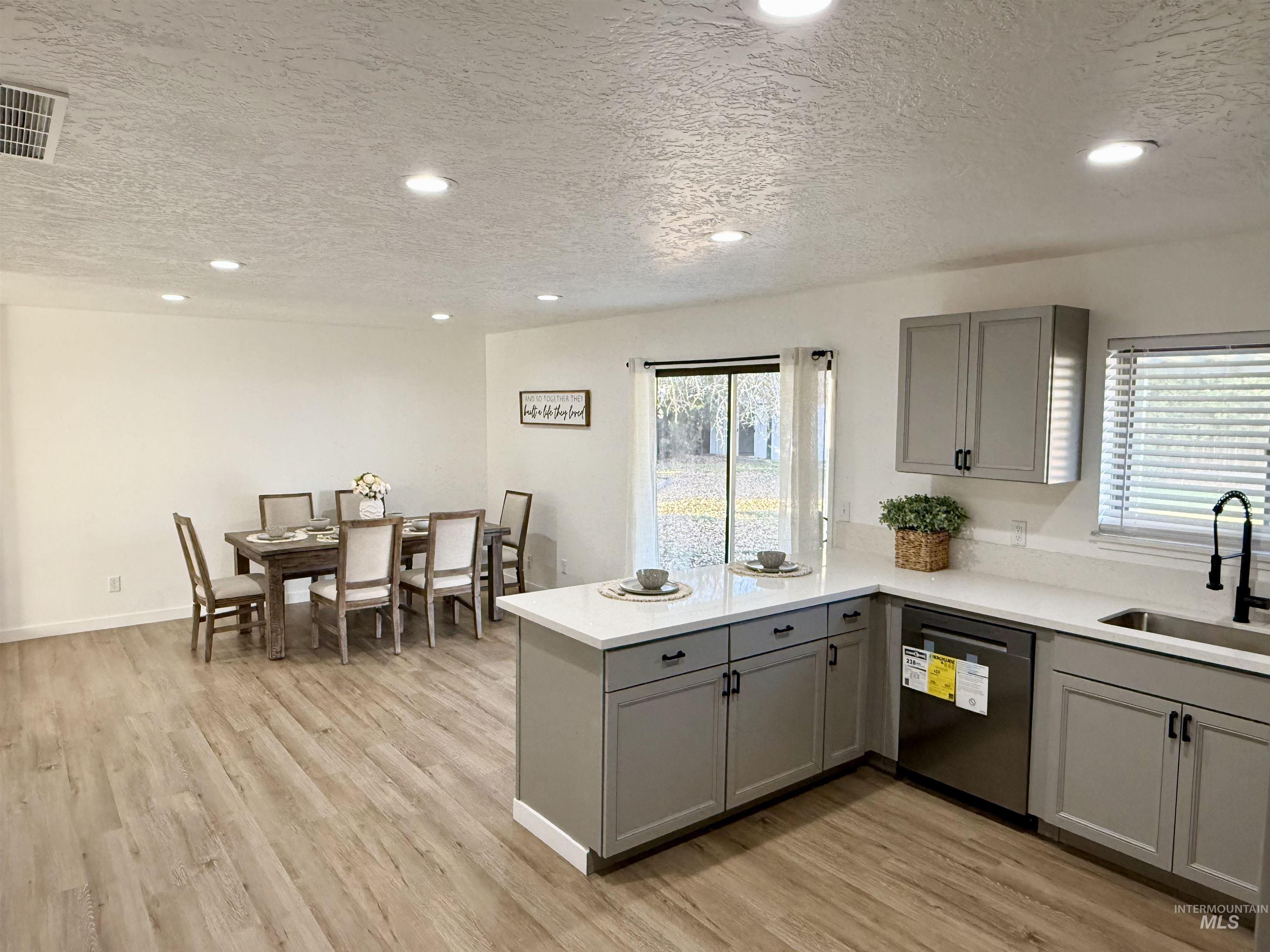 Kitchen featuring gray cabinets, recessed lighting, a peninsula, a textured ceiling, and stainless steel dishwasher