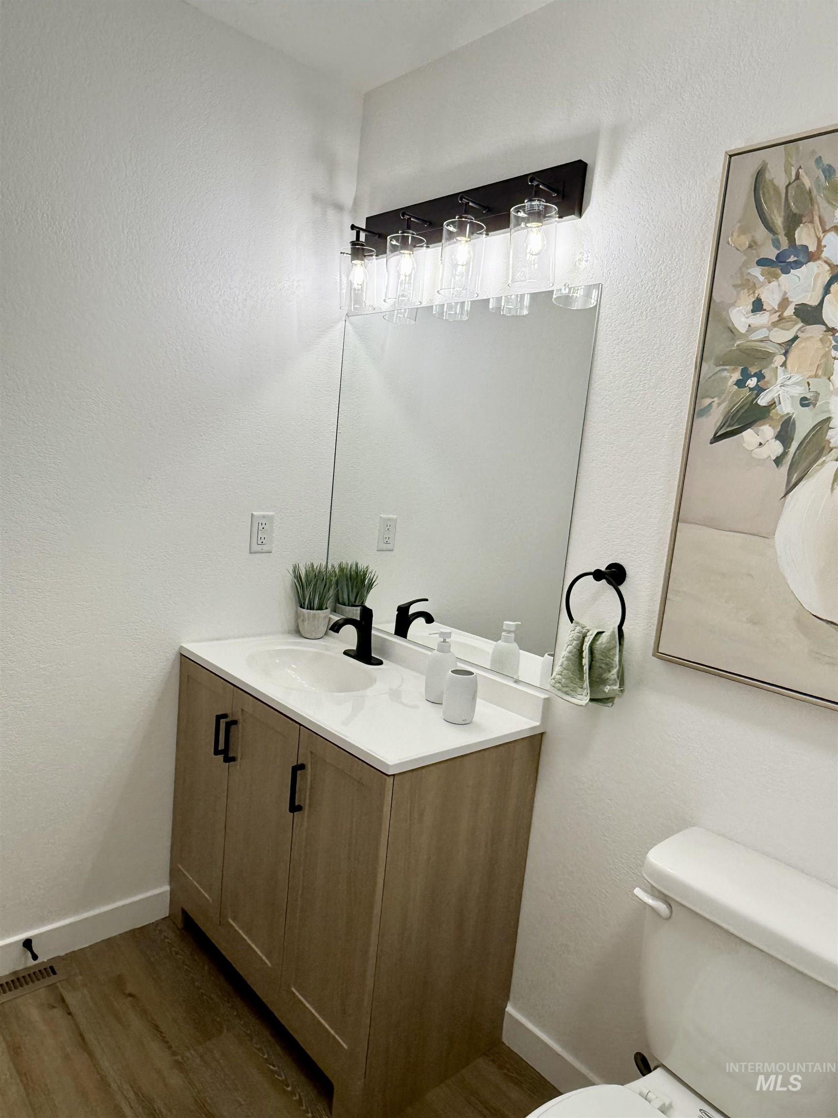 Half bathroom with vanity, dark wood-style flooring, and a textured wall