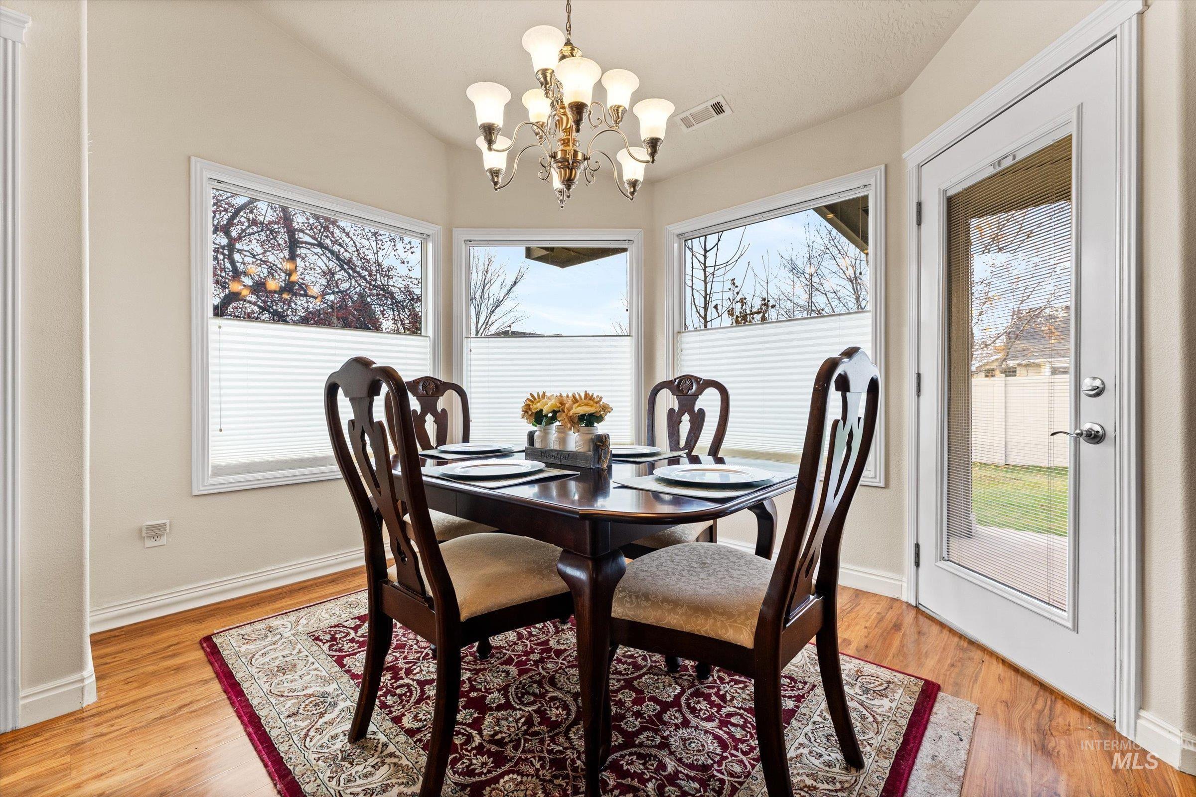 Dining space with plenty of natural light, a chandelier, light wood-style flooring, and lofted ceiling