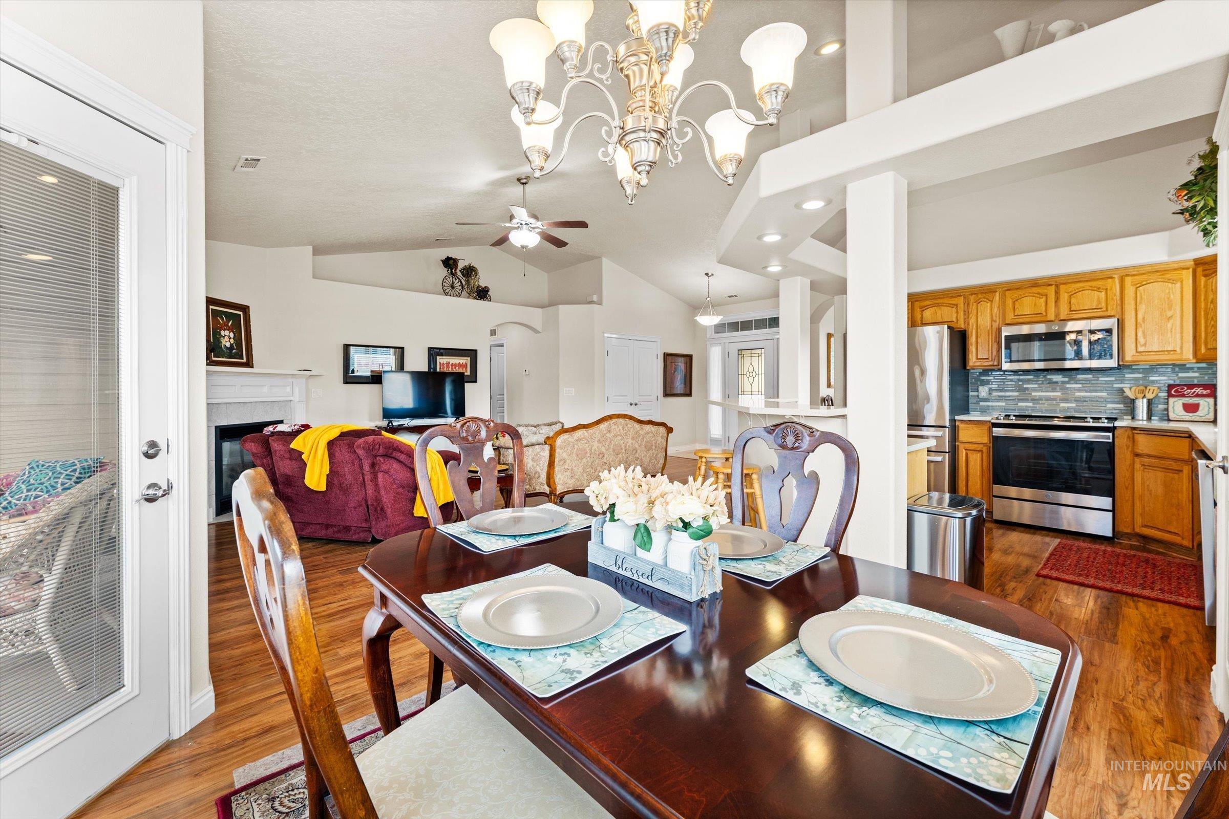 Dining room featuring dark wood-style floors, lofted ceiling, a ceiling fan, recessed lighting, and a chandelier