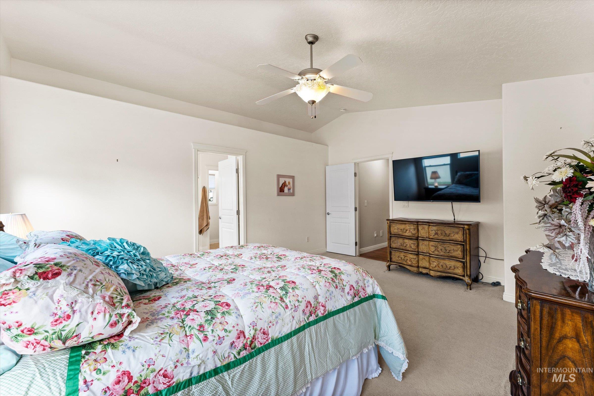 Carpeted bedroom featuring vaulted ceiling and ceiling fan