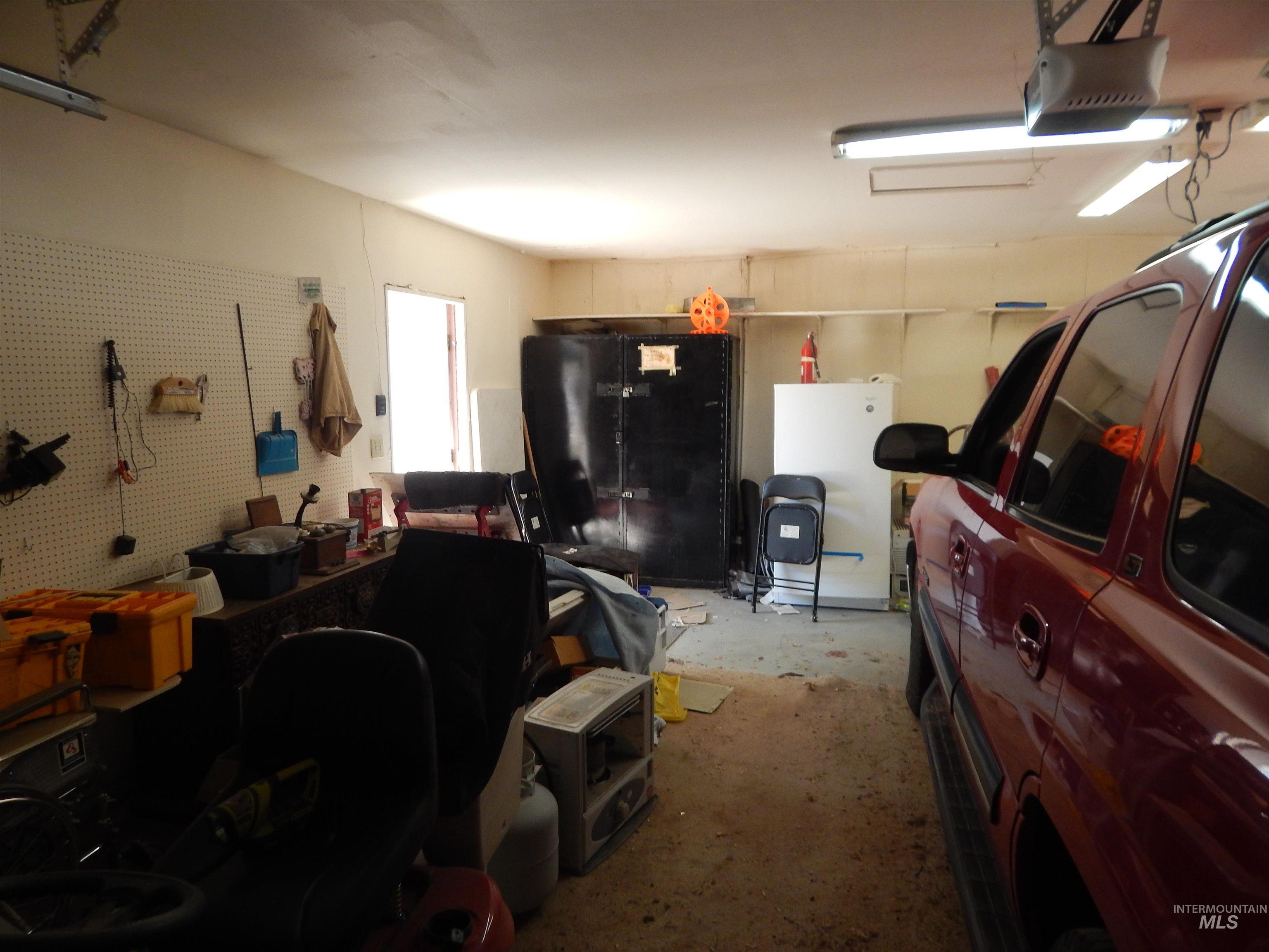 Garage with a workshop area, a garage door opener, and freestanding refrigerator