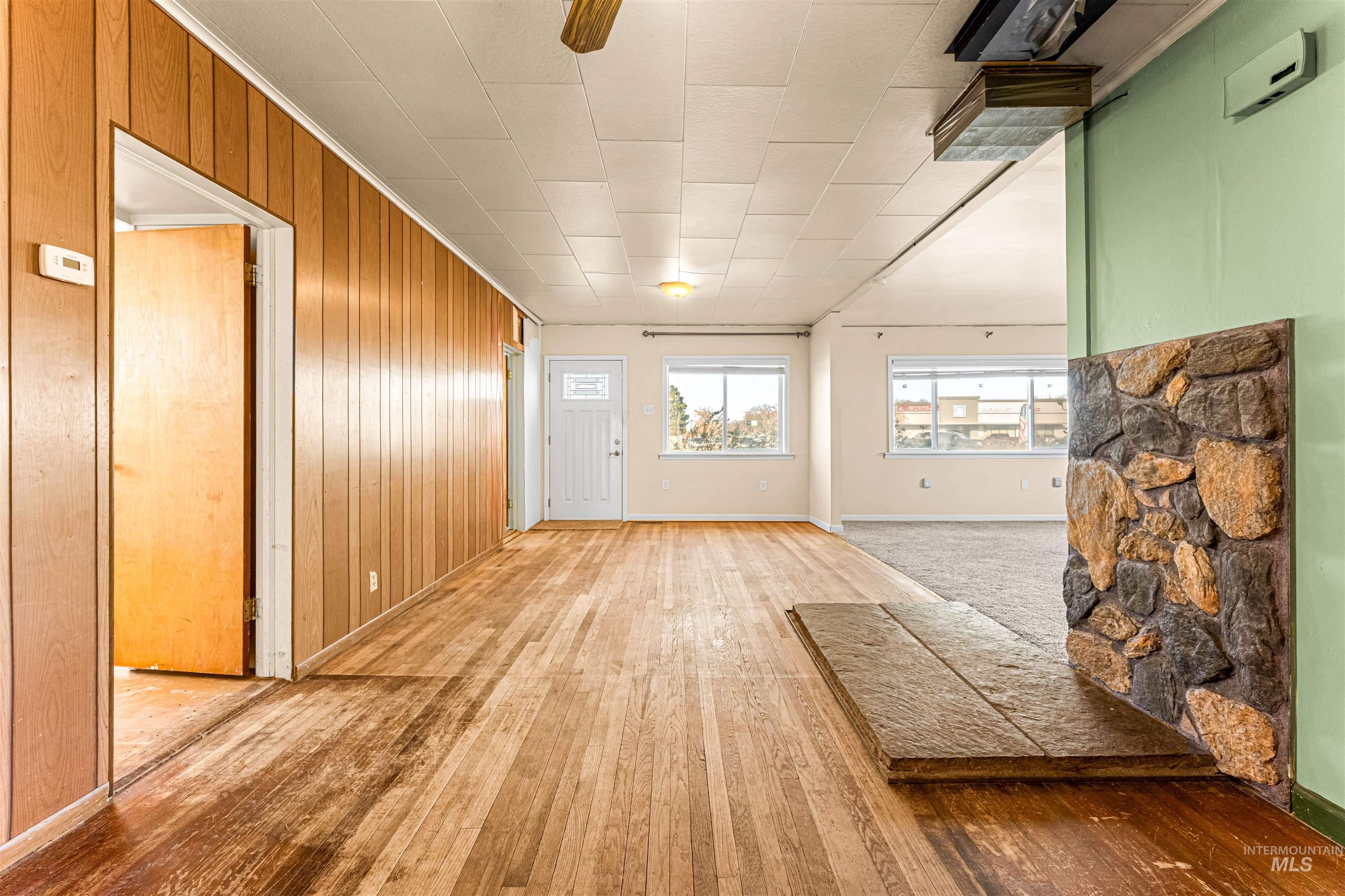 Unfurnished living room with wooden walls, light wood-style floors, and ornamental molding
