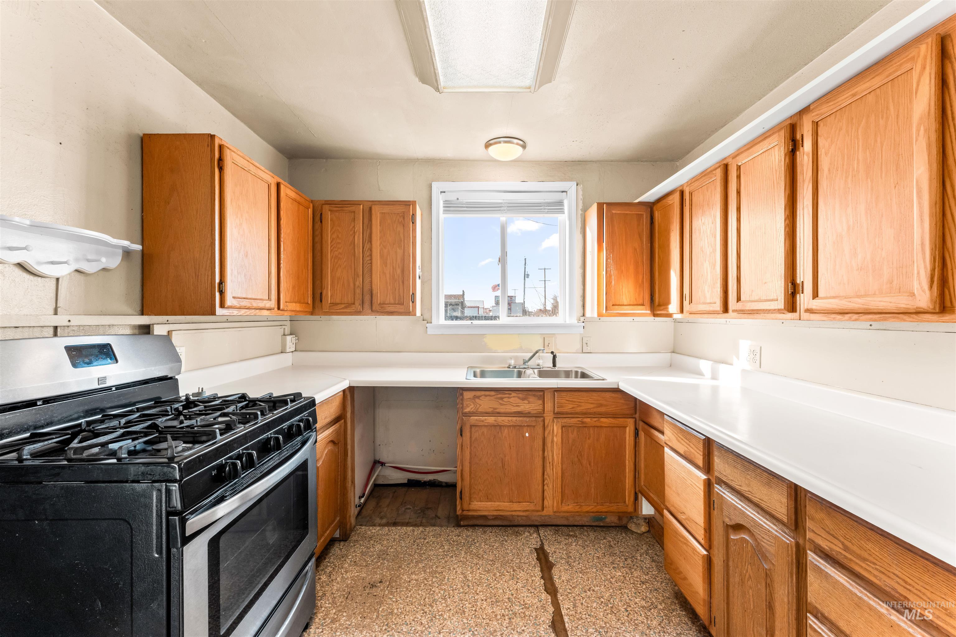 Kitchen with stainless steel range with gas stovetop, light countertops, and brown cabinets