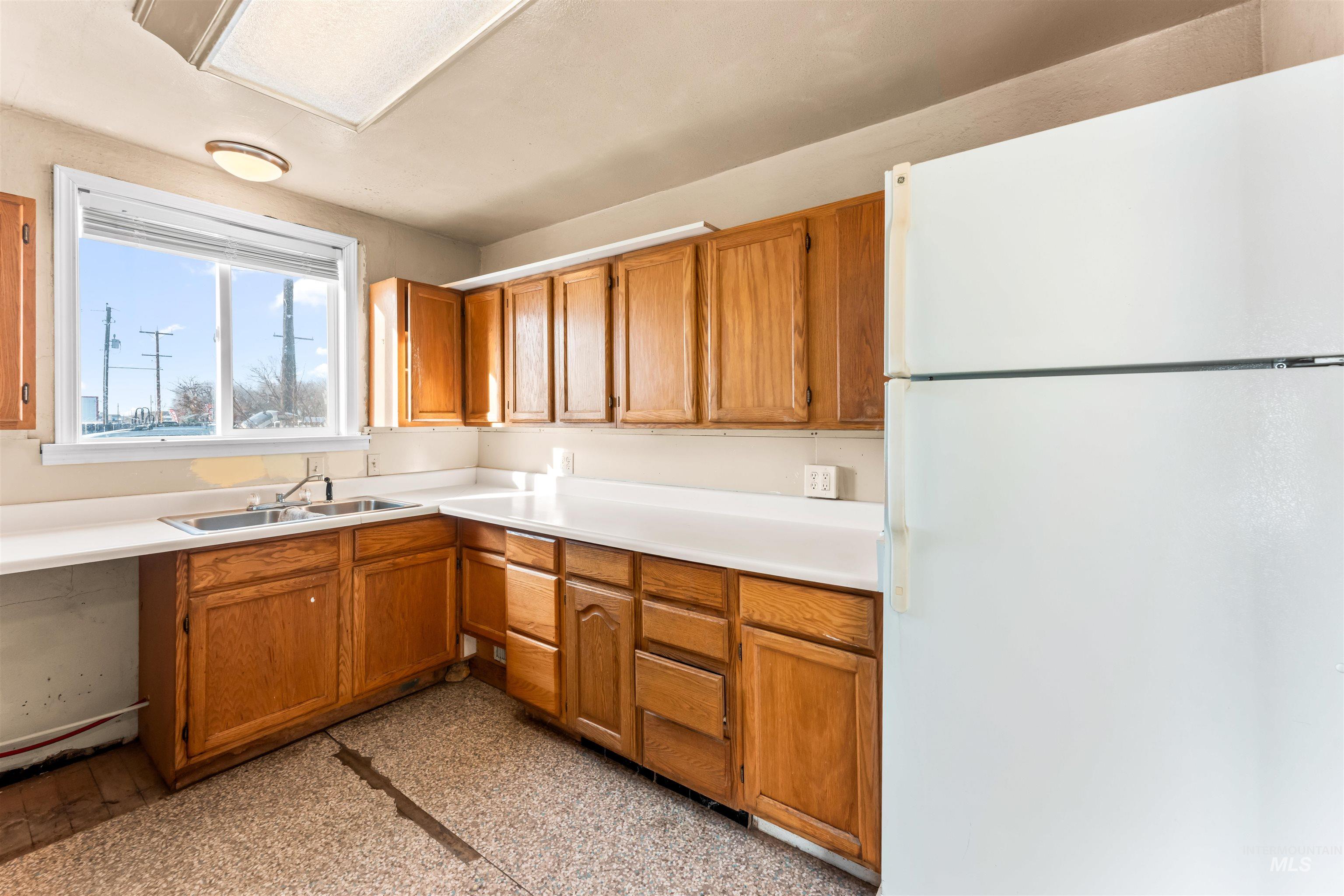 Kitchen with freestanding refrigerator, light countertops, and brown cabinetry