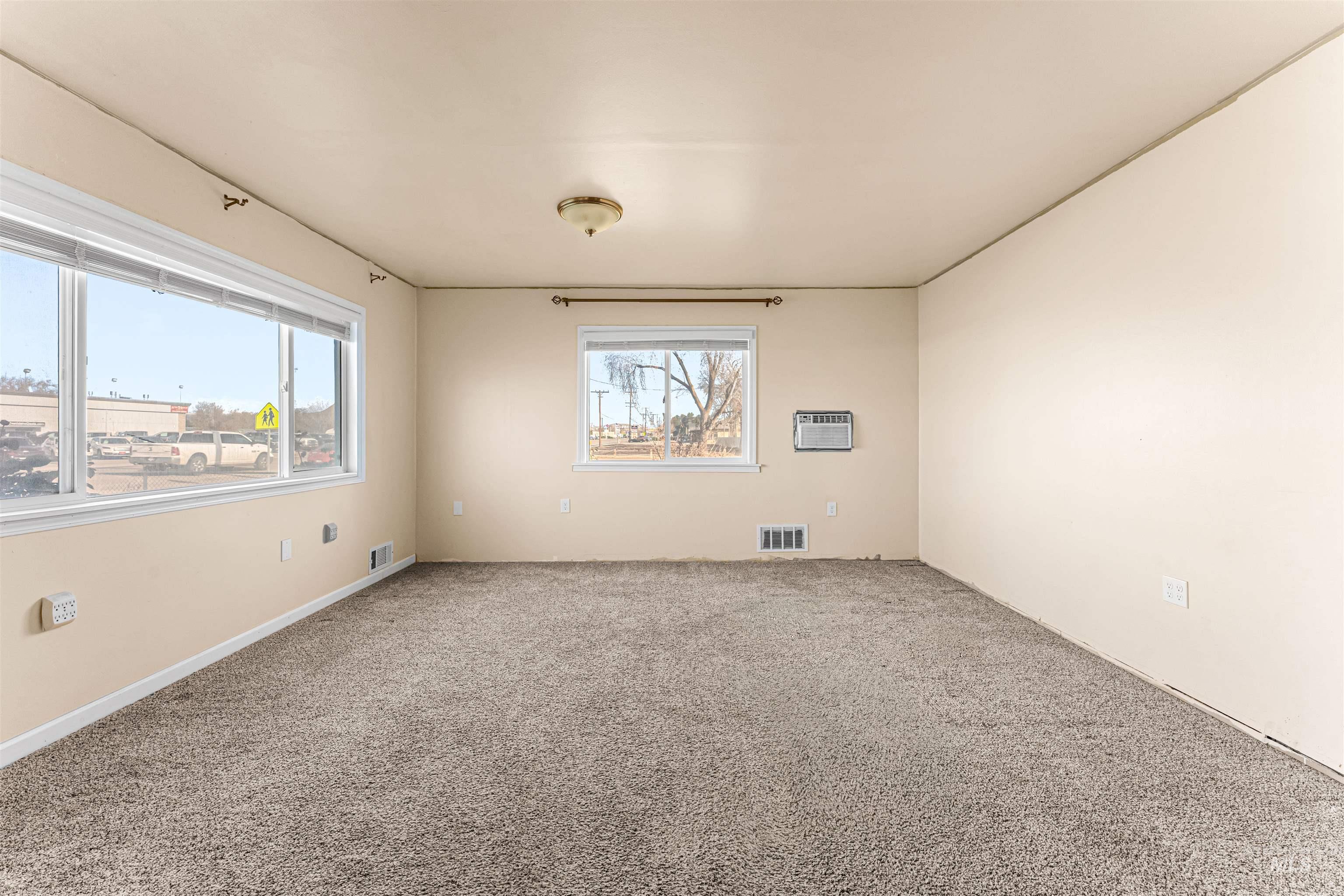 Carpeted empty room with plenty of natural light and an AC wall unit