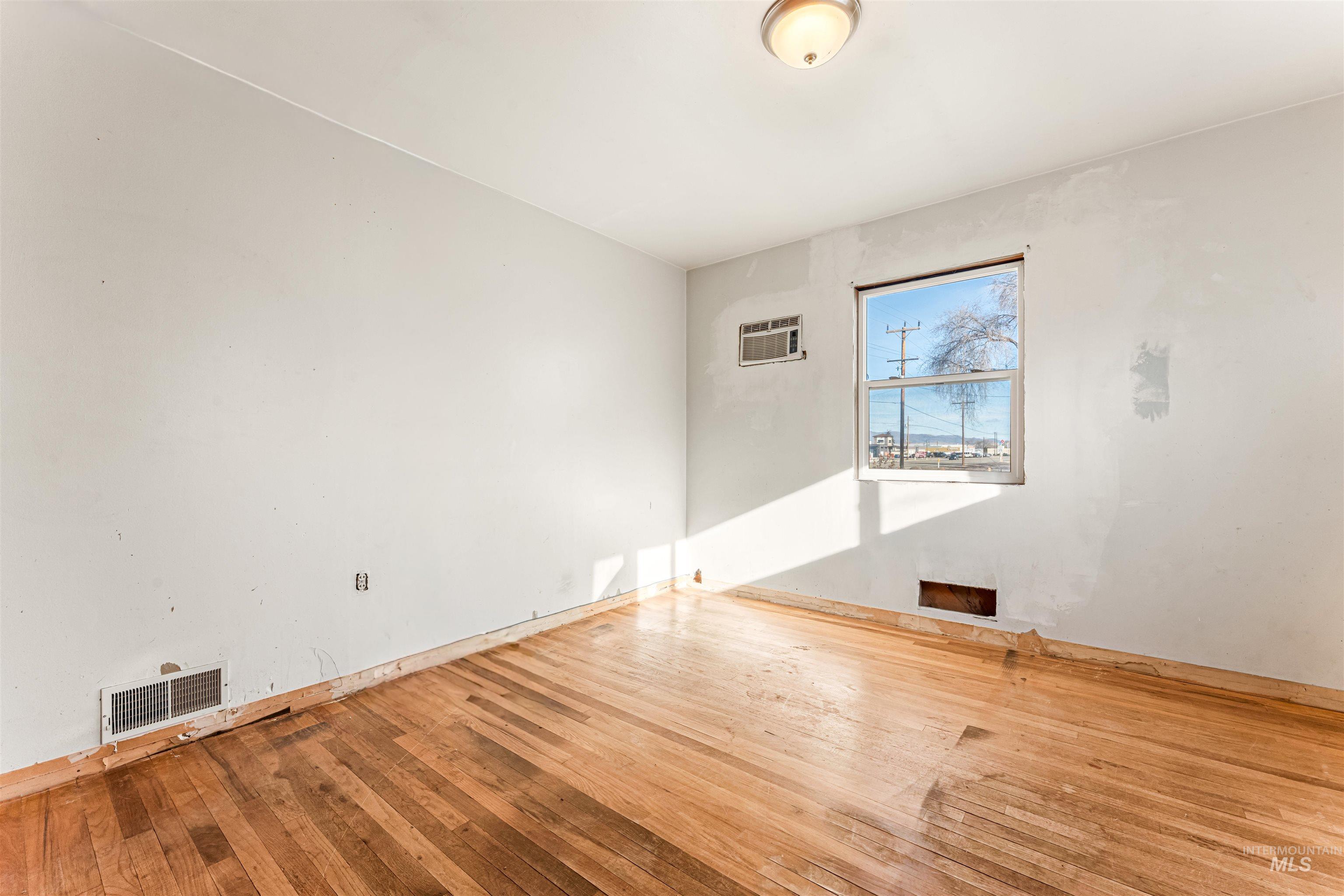 Unfurnished room featuring hardwood / wood-style flooring and an AC wall unit