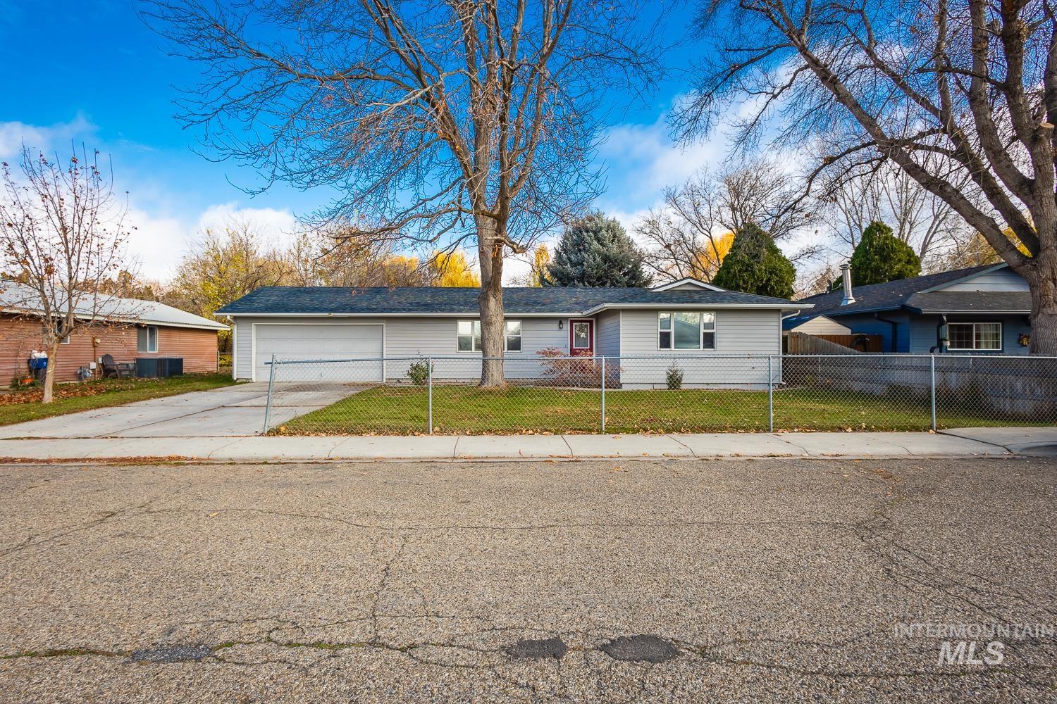 Ranch-style home featuring driveway, a fenced front yard, and an attached garage