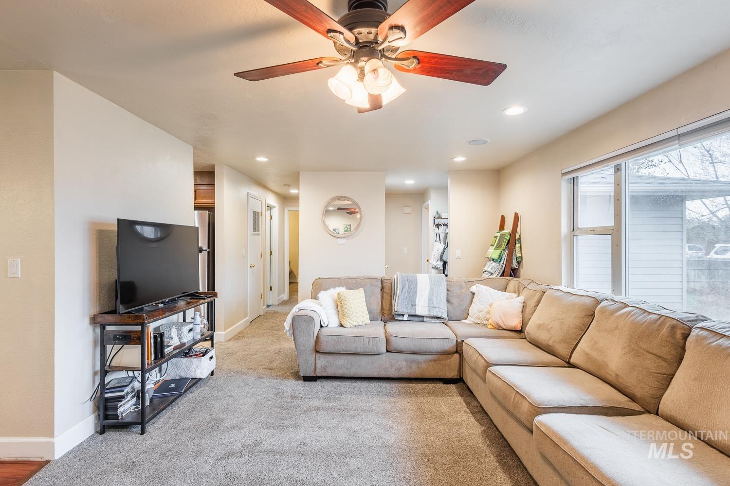 Living area featuring recessed lighting, light colored carpet, and a ceiling fan