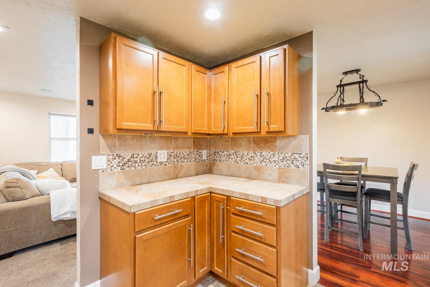 Kitchen with decorative backsplash, open floor plan, tile counters, and brown cabinets