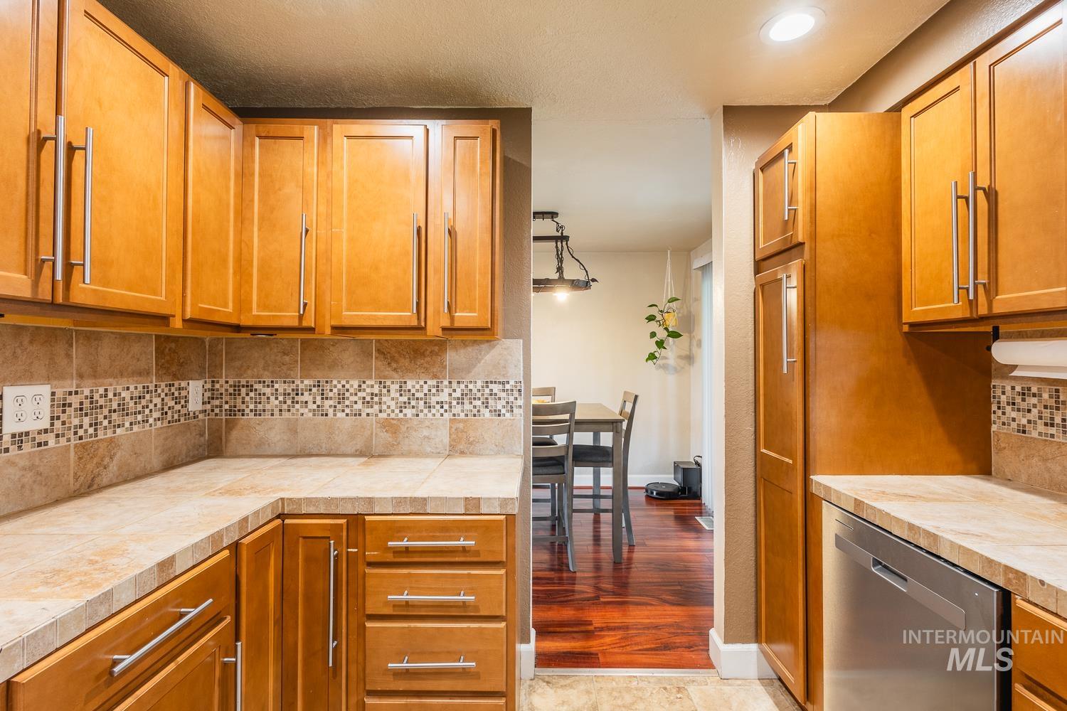 Kitchen featuring backsplash, brown cabinets, and stainless steel dishwasher