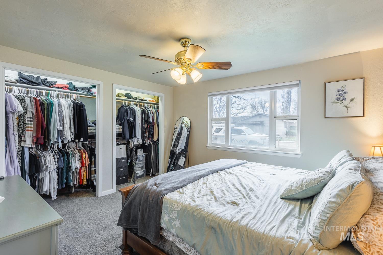 Carpeted bedroom featuring a ceiling fan and two closets