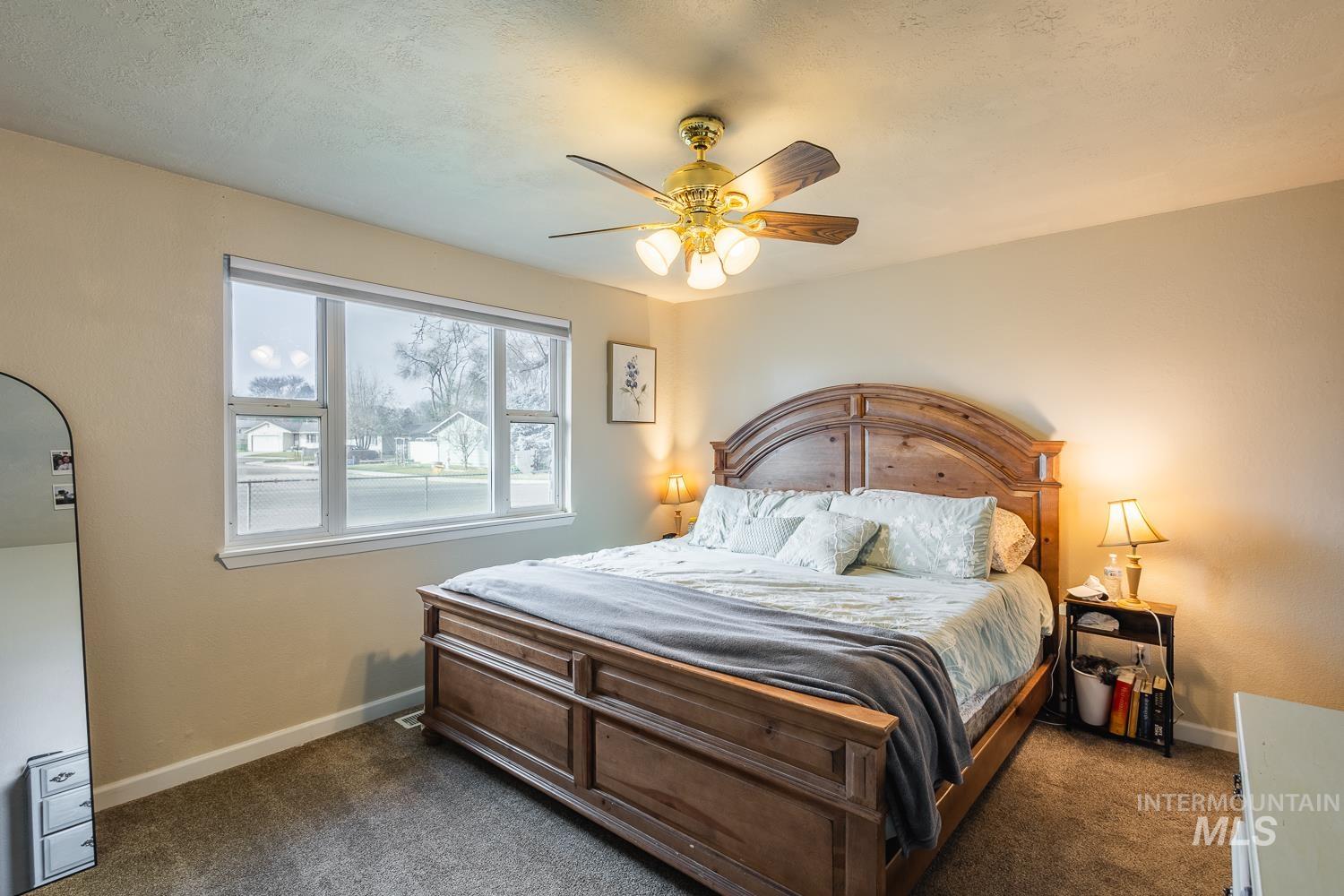 Bedroom featuring dark colored carpet, ceiling fan, and a textured ceiling
