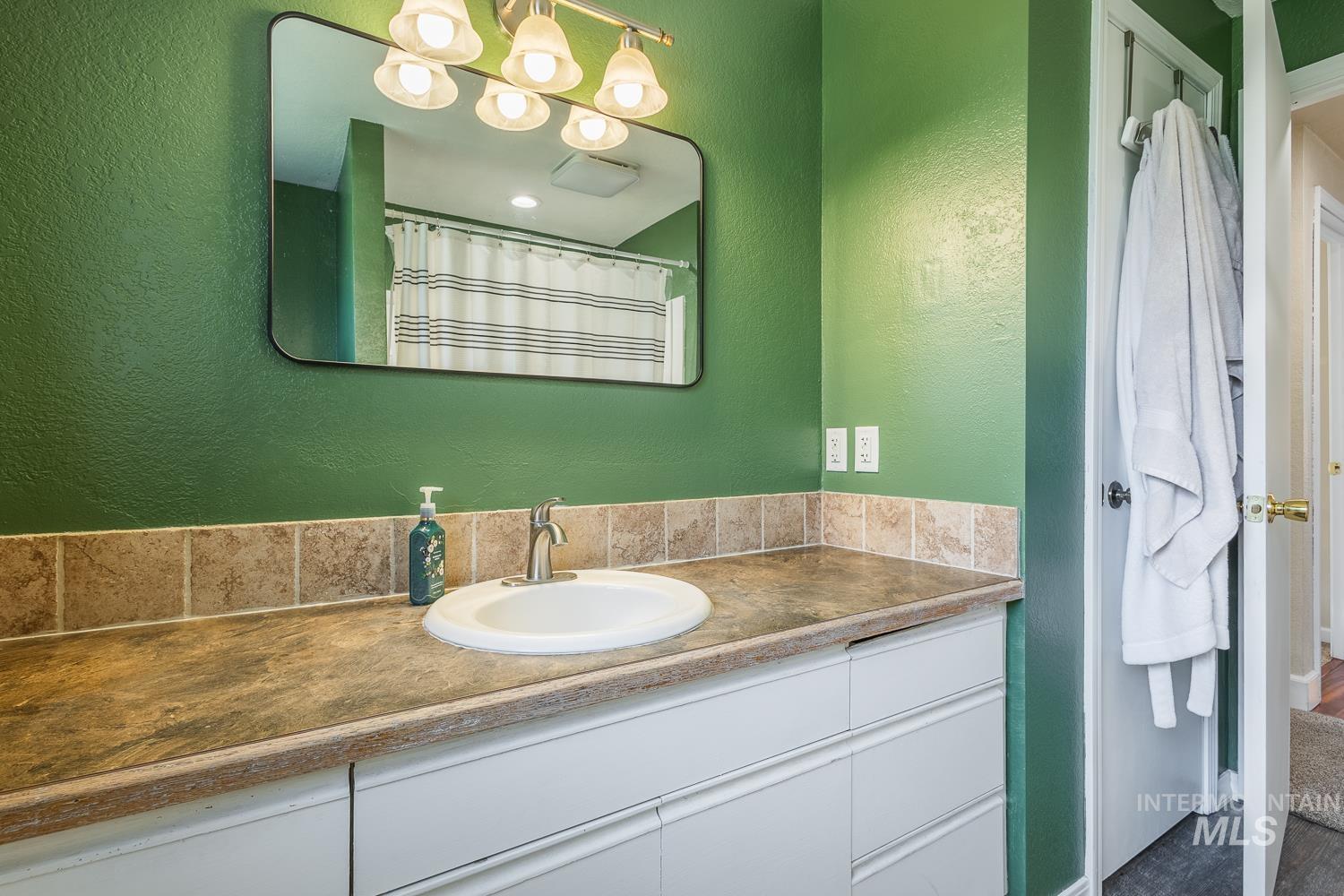 Full bathroom with a textured wall, a shower with shower curtain, and vanity