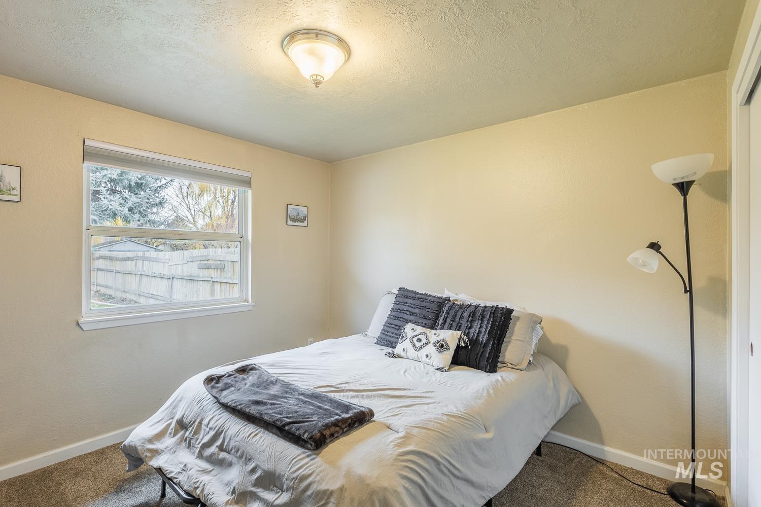 Carpeted bedroom featuring a textured ceiling and baseboards