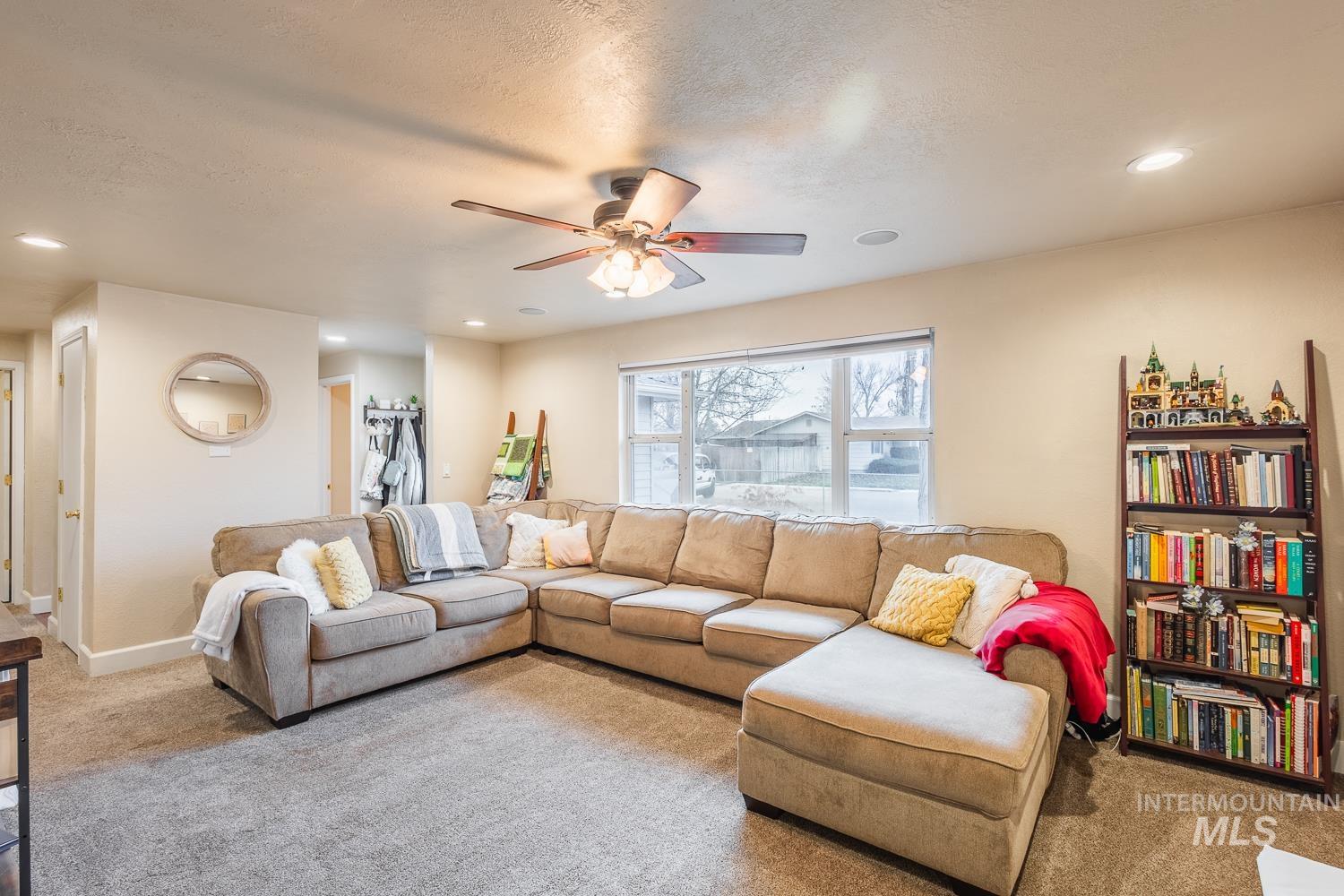 Carpeted living area featuring recessed lighting, ceiling fan, and a textured ceiling