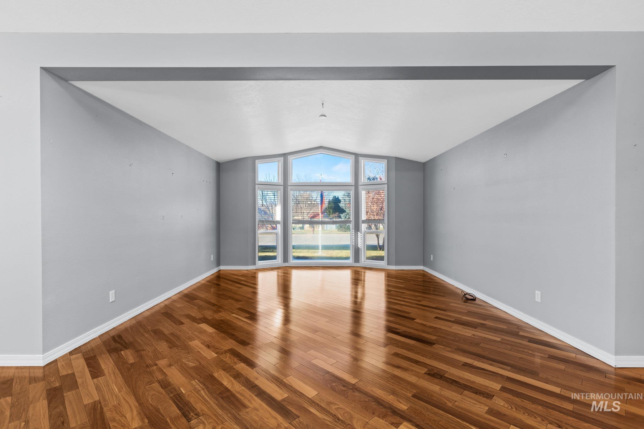 Spare room with wood finished floors and vaulted ceiling