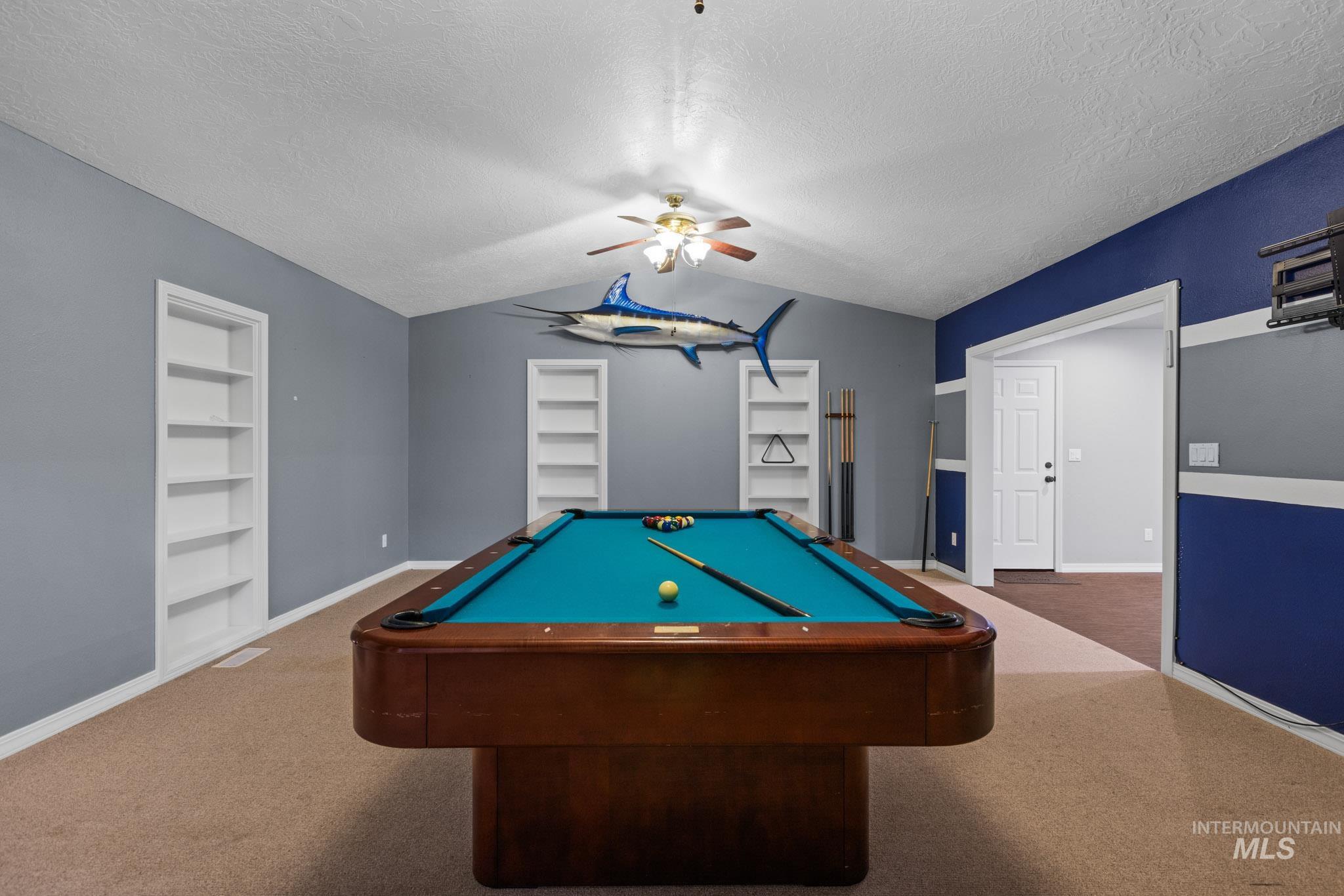 Rec room with built in shelves, pool table, a textured ceiling, lofted ceiling, and a ceiling fan