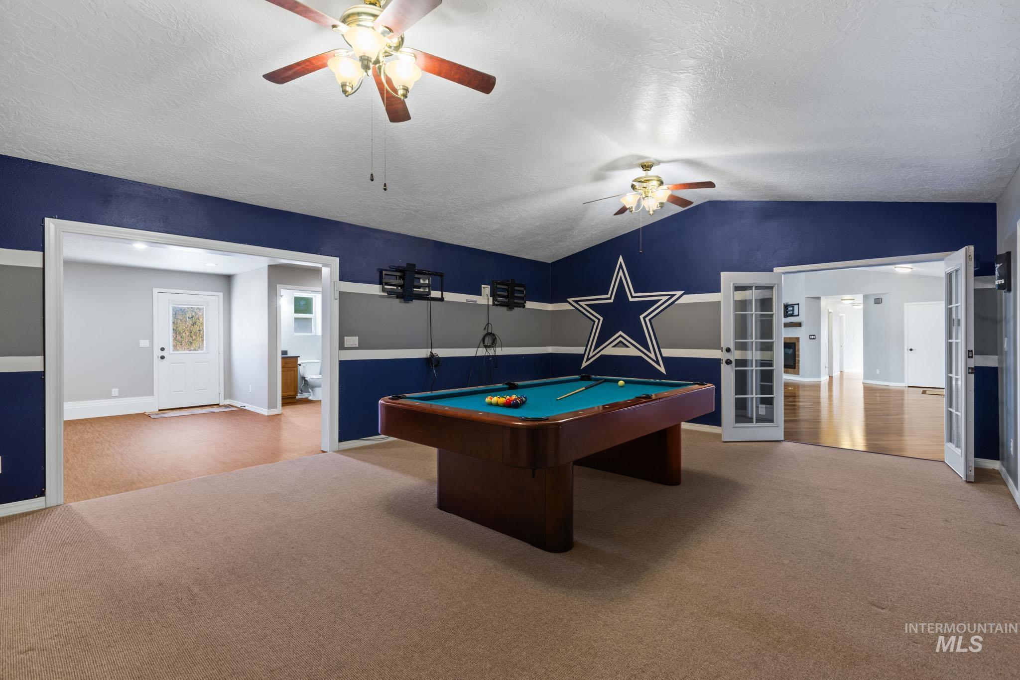 Rec room with pool table, light colored carpet, vaulted ceiling, a textured ceiling, and ceiling fan