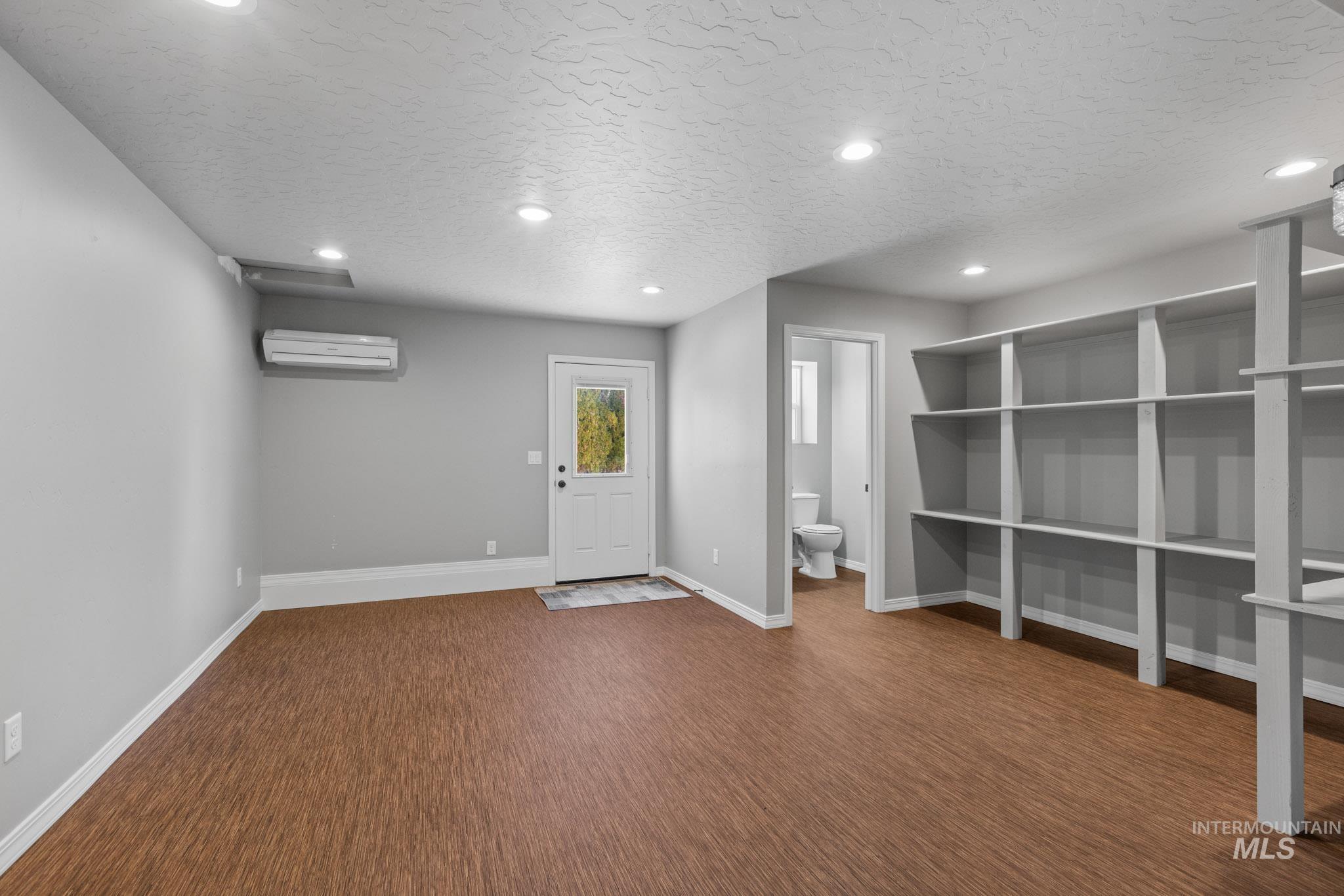 recessed lighting, dark wood finished floors, and an AC wall unit