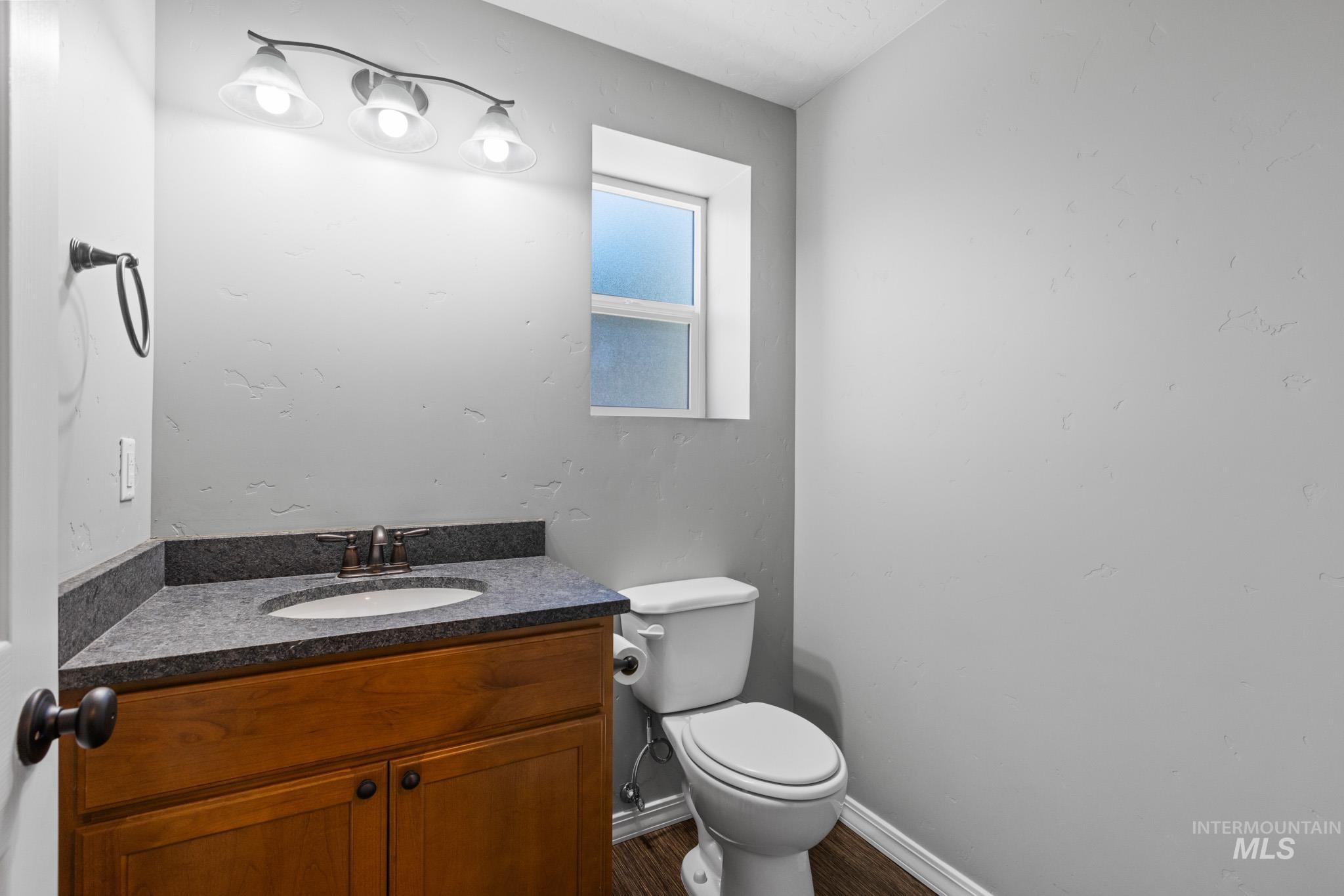 Half bathroom featuring vanity and dark wood-type flooring
