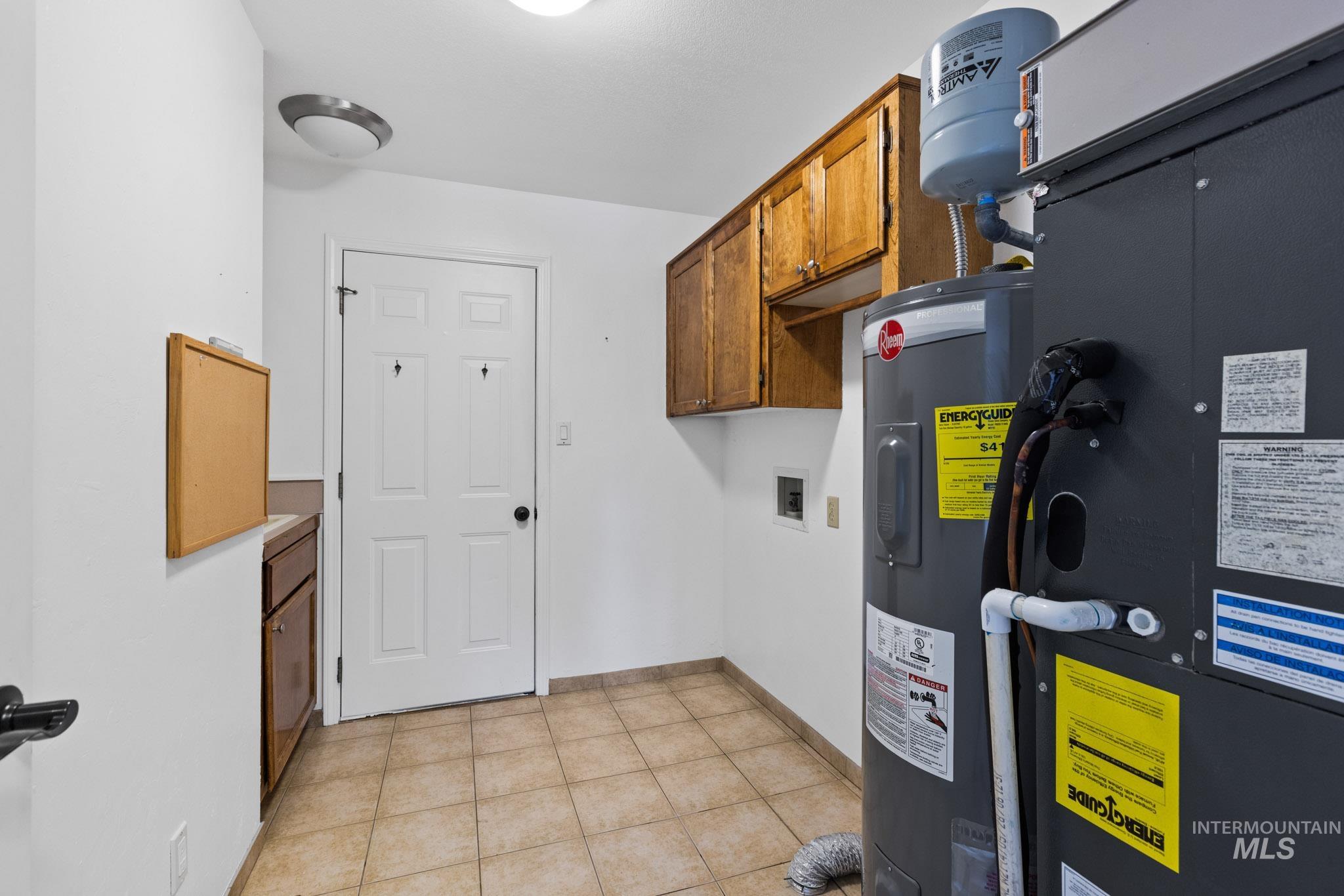 Utility room featuring heating unit and electric water heater