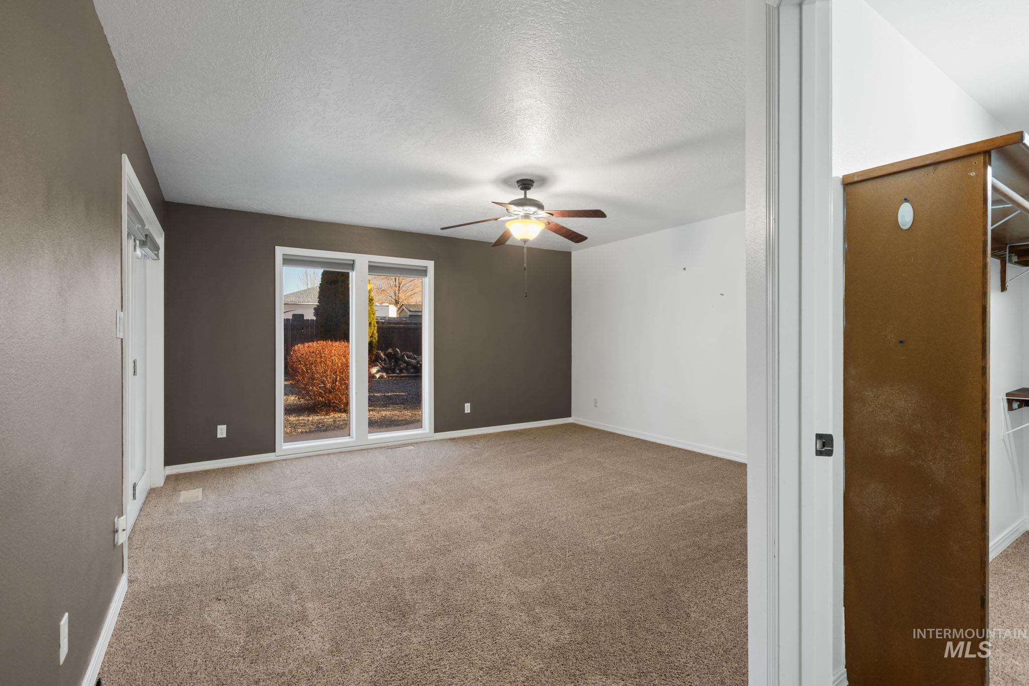 Master bedroom with a textured ceiling, light colored carpet, and ceiling fan