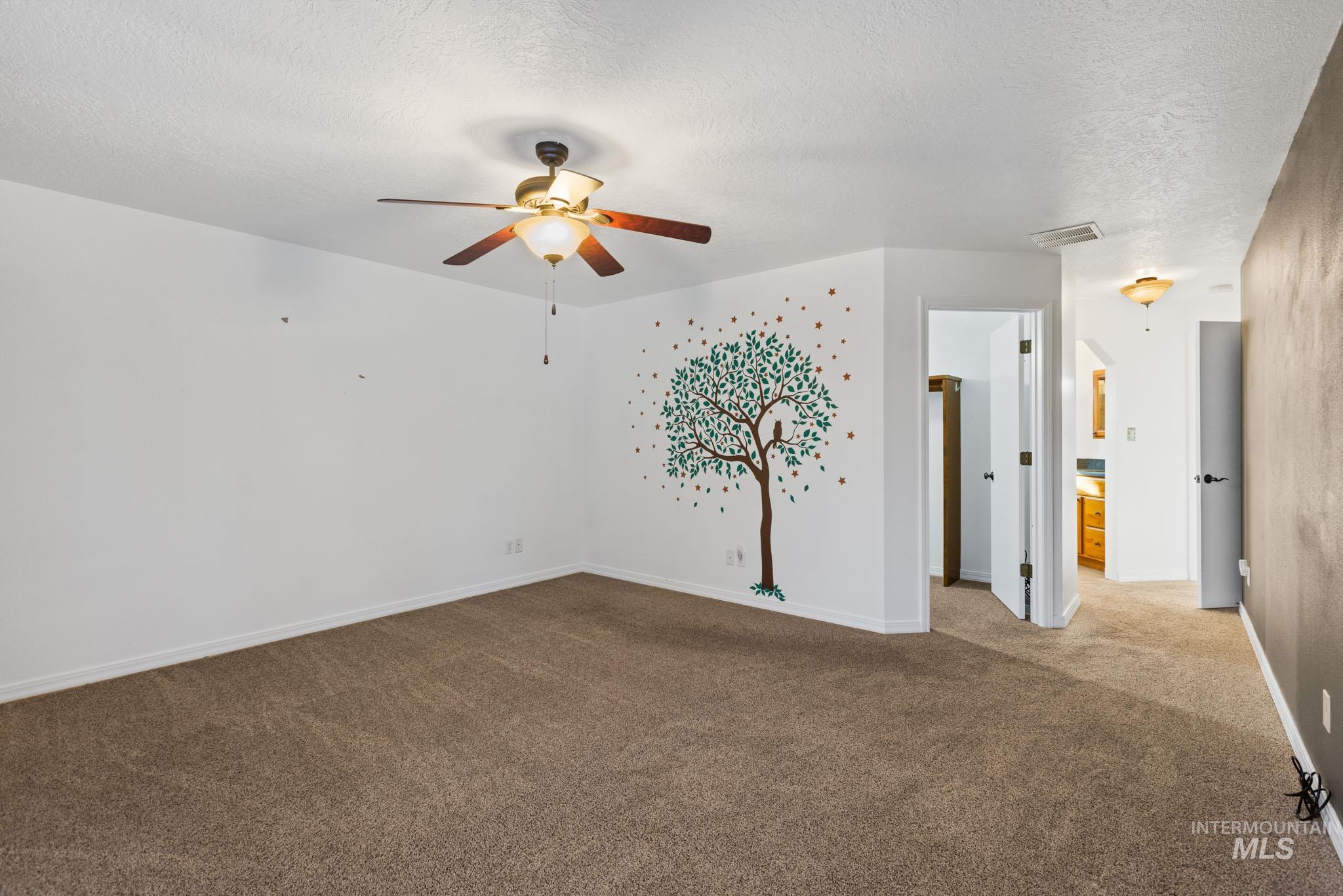 Master bedroom featuring carpet floors, a textured ceiling, and a ceiling fan