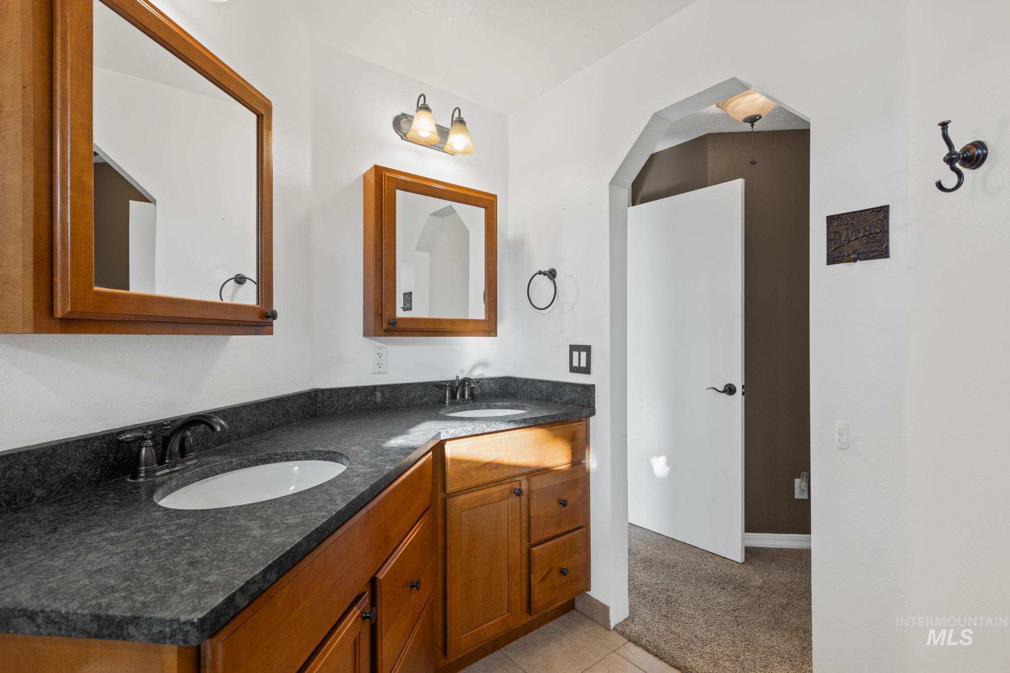 Bathroom featuring double vanity, light carpet, and light tile patterned floors