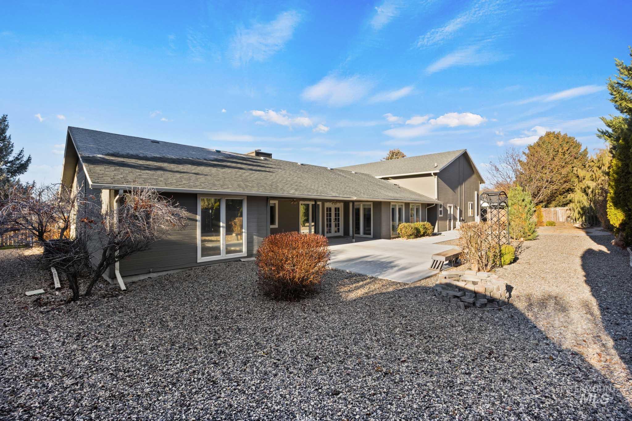 Rear view of house with a shingled roof, a chimney, french doors, and a patio area