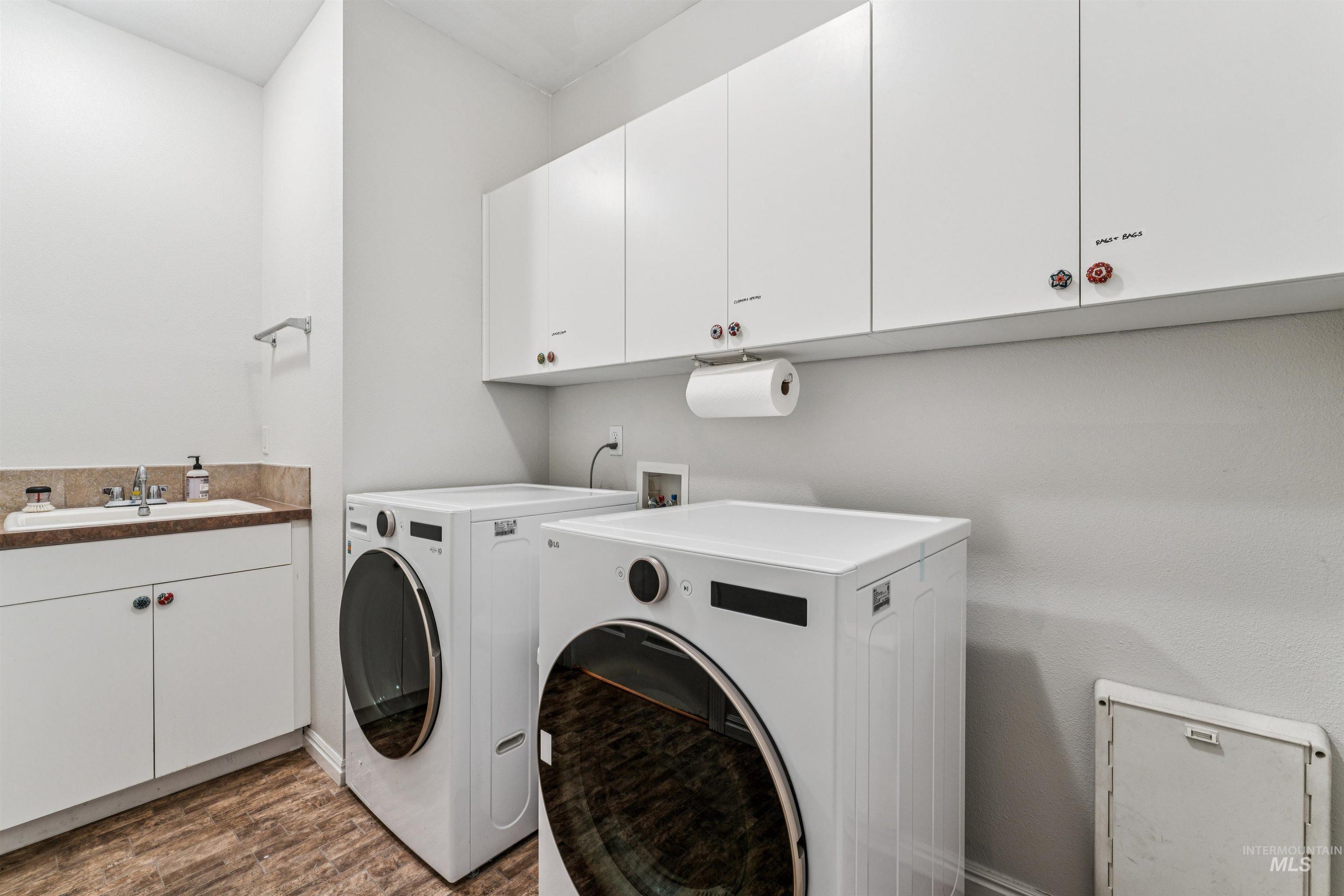 Laundry room with cabinet space, dark wood-type flooring, and washer and clothes dryer