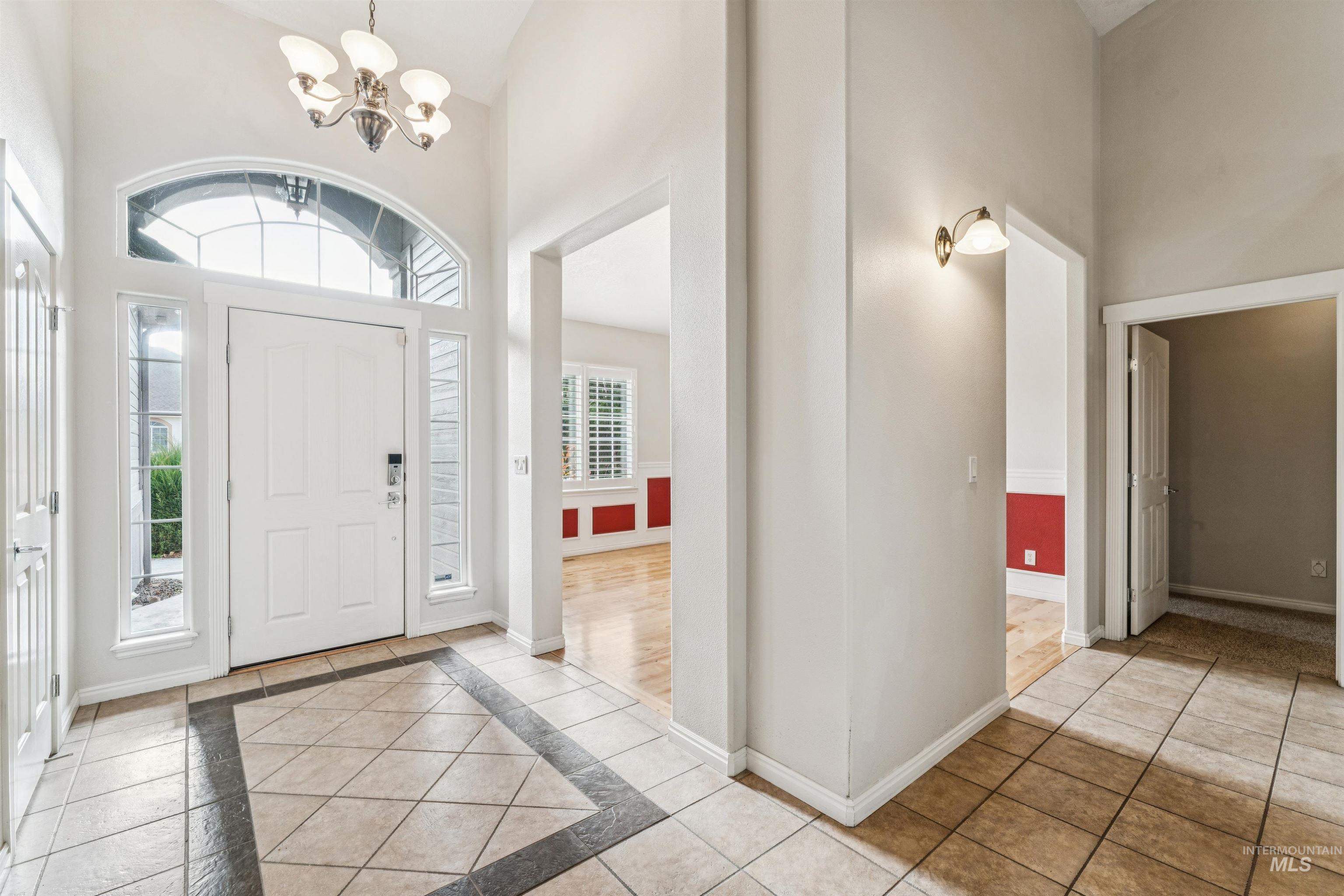 Foyer featuring inlaid floor details, a high ceiling, a chandelier, and tile patterned floors