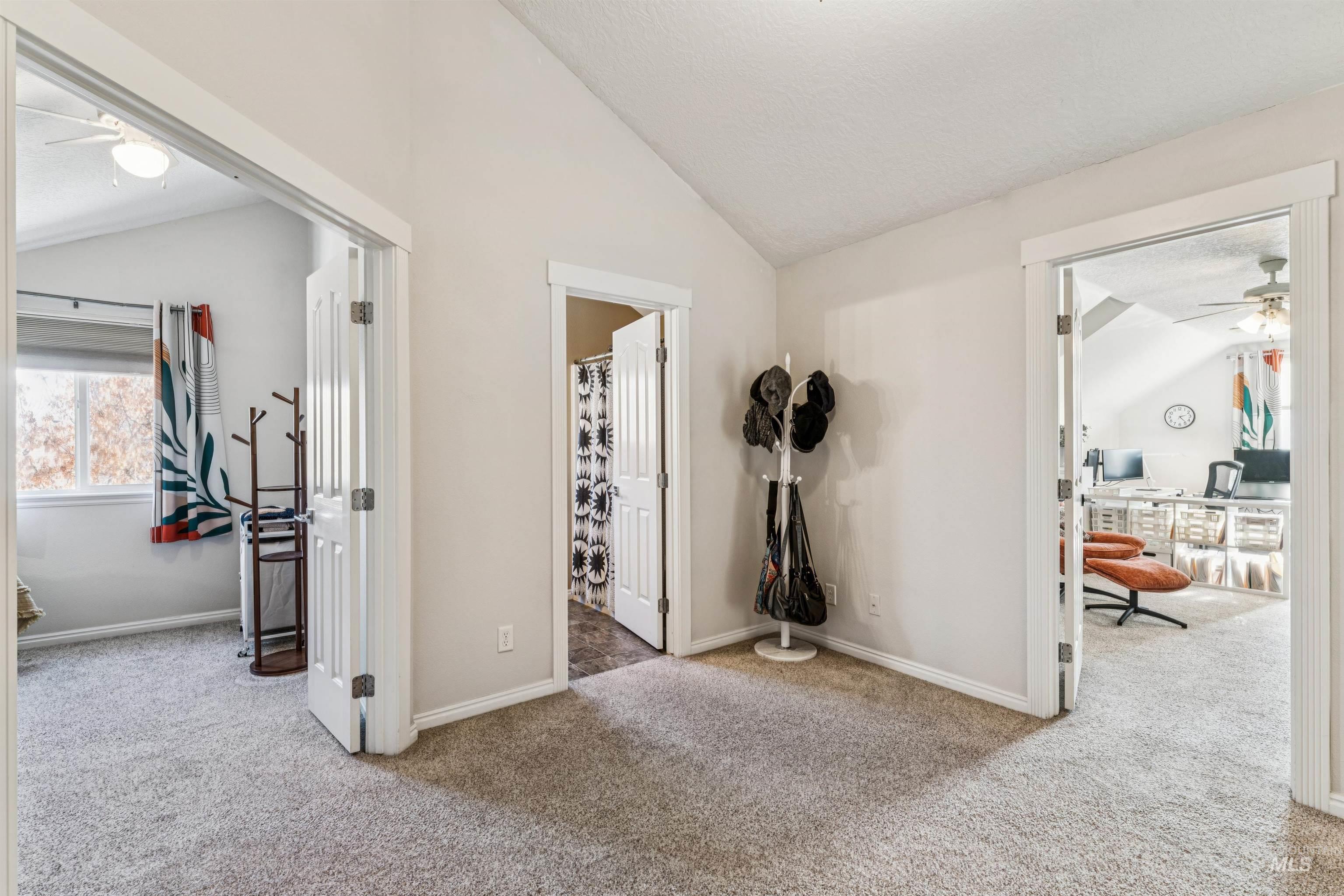 Hall with light carpet, an office area, lofted ceiling, and a textured ceiling