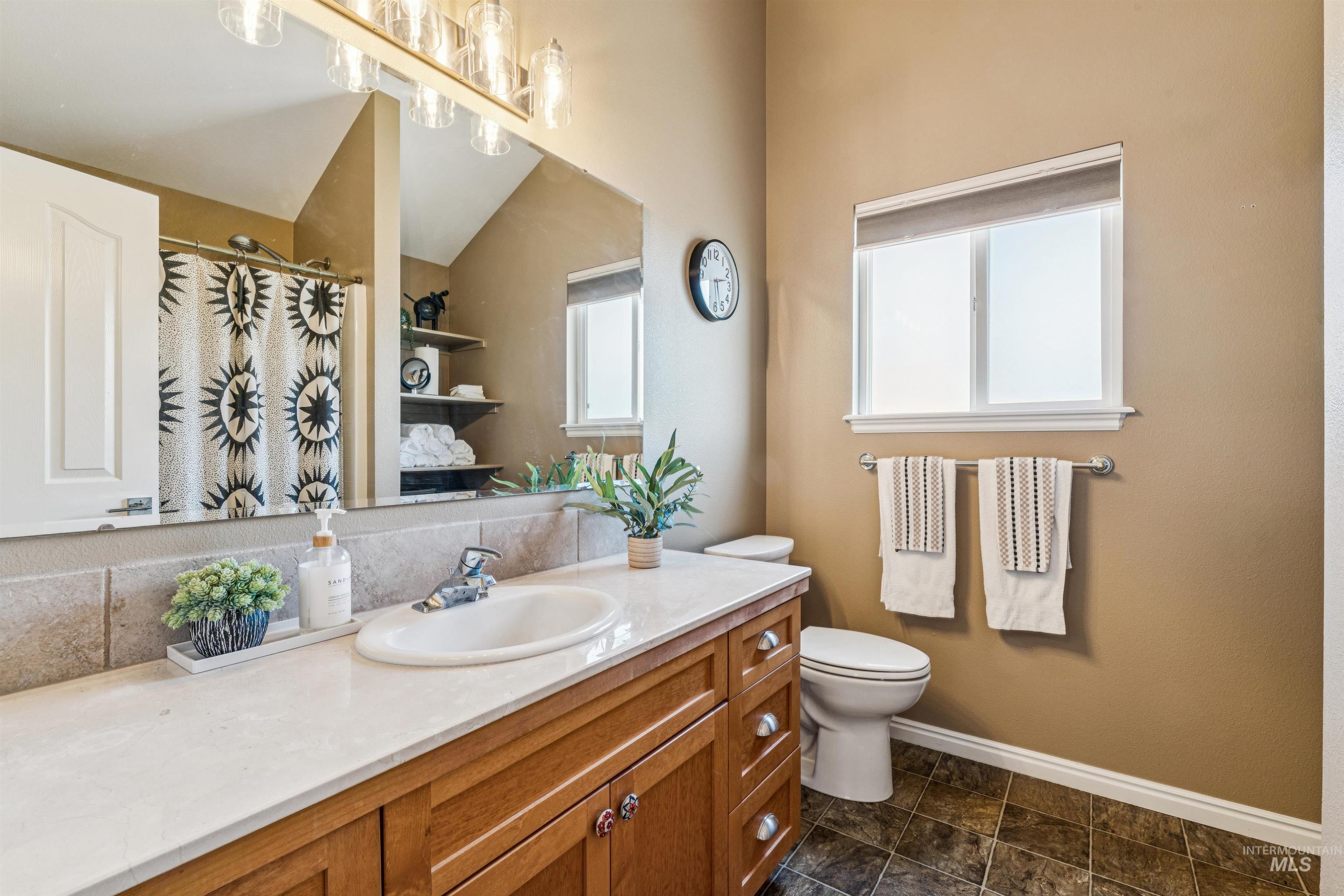 Full bath featuring a shower with curtain, vanity, and vaulted ceiling