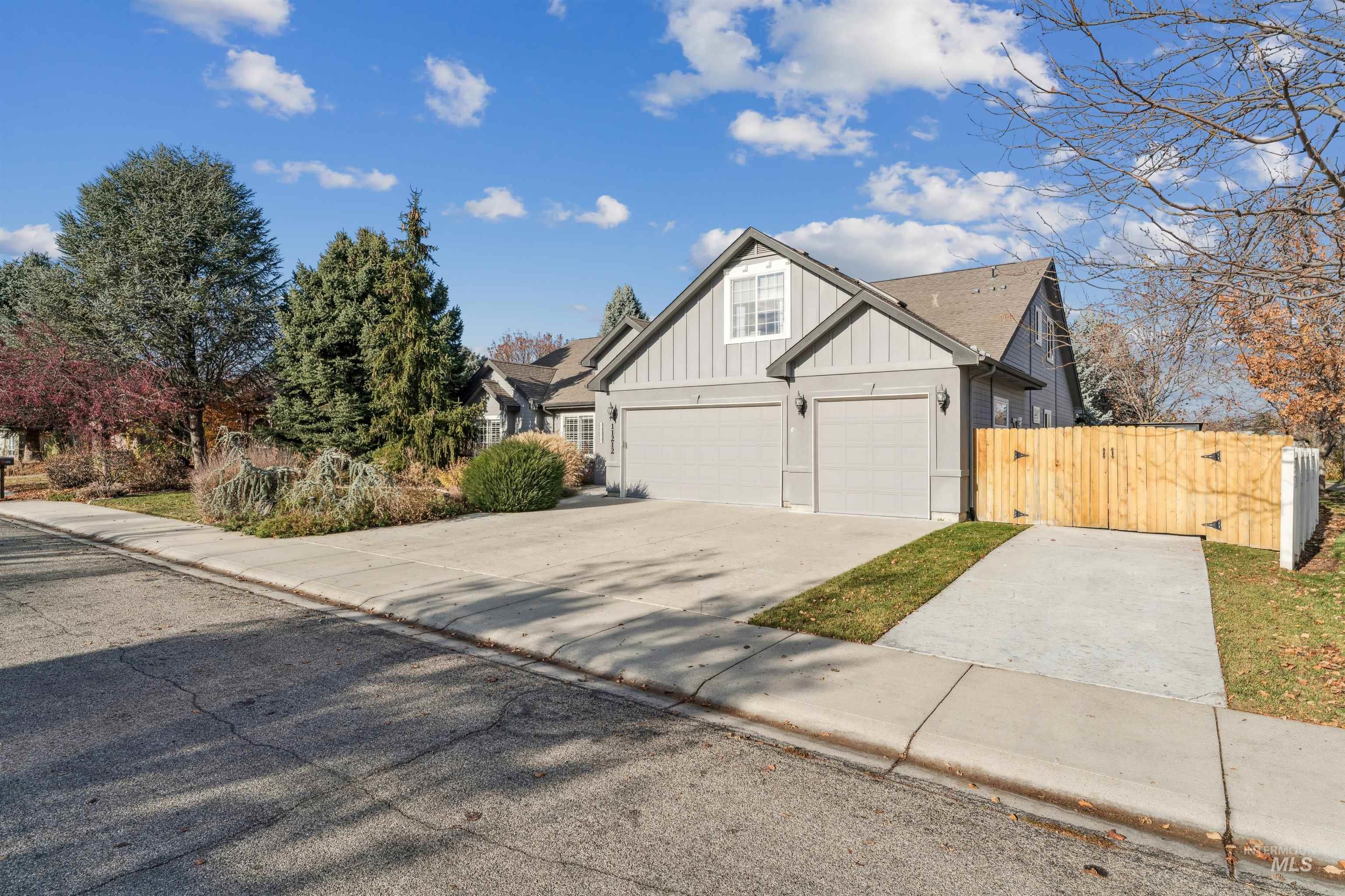 View of front facade featuring board and batten siding, concrete driveway, and a gate