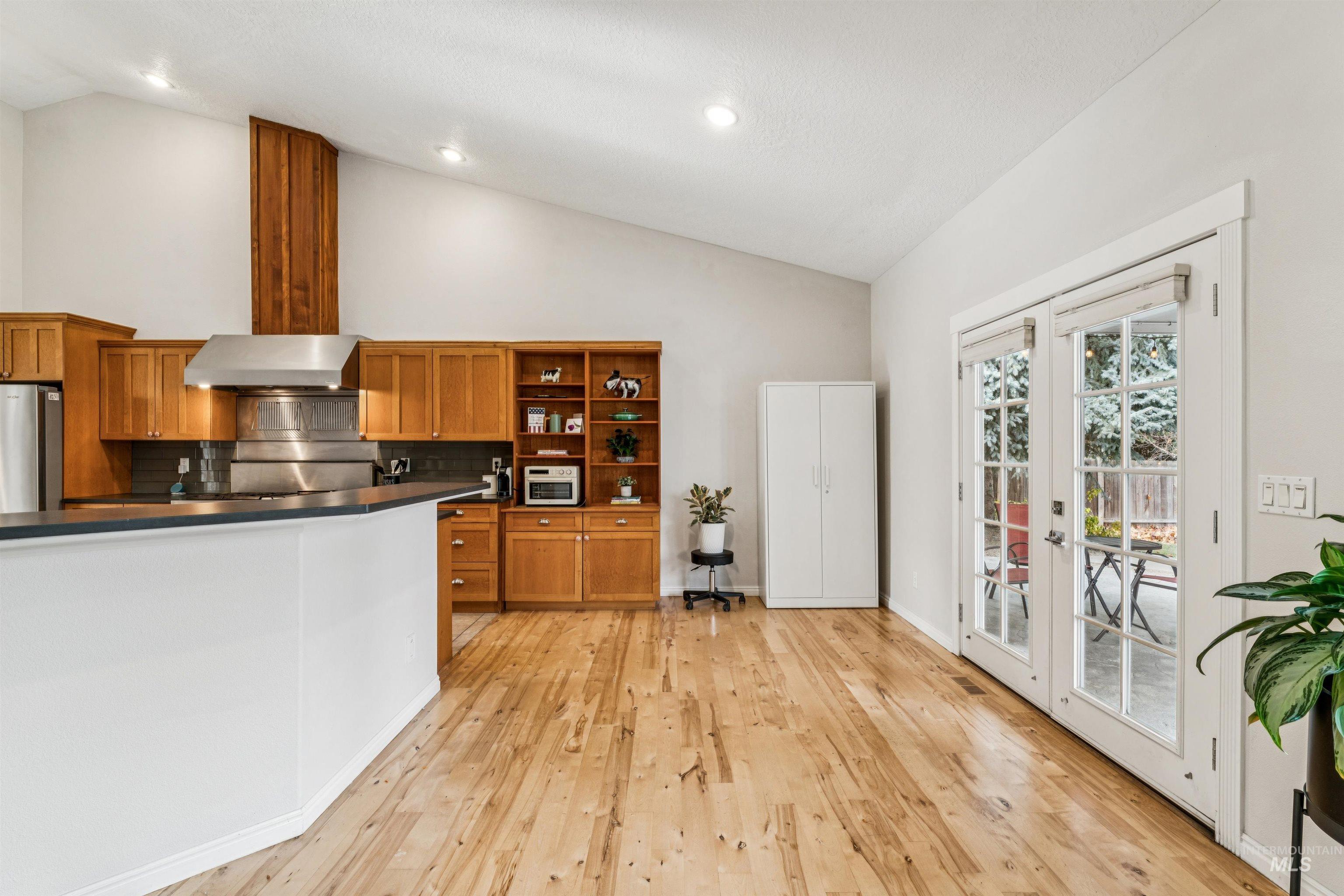 Kitchen with brown cabinets, dark countertops, tasteful backsplash, open shelves, and french doors