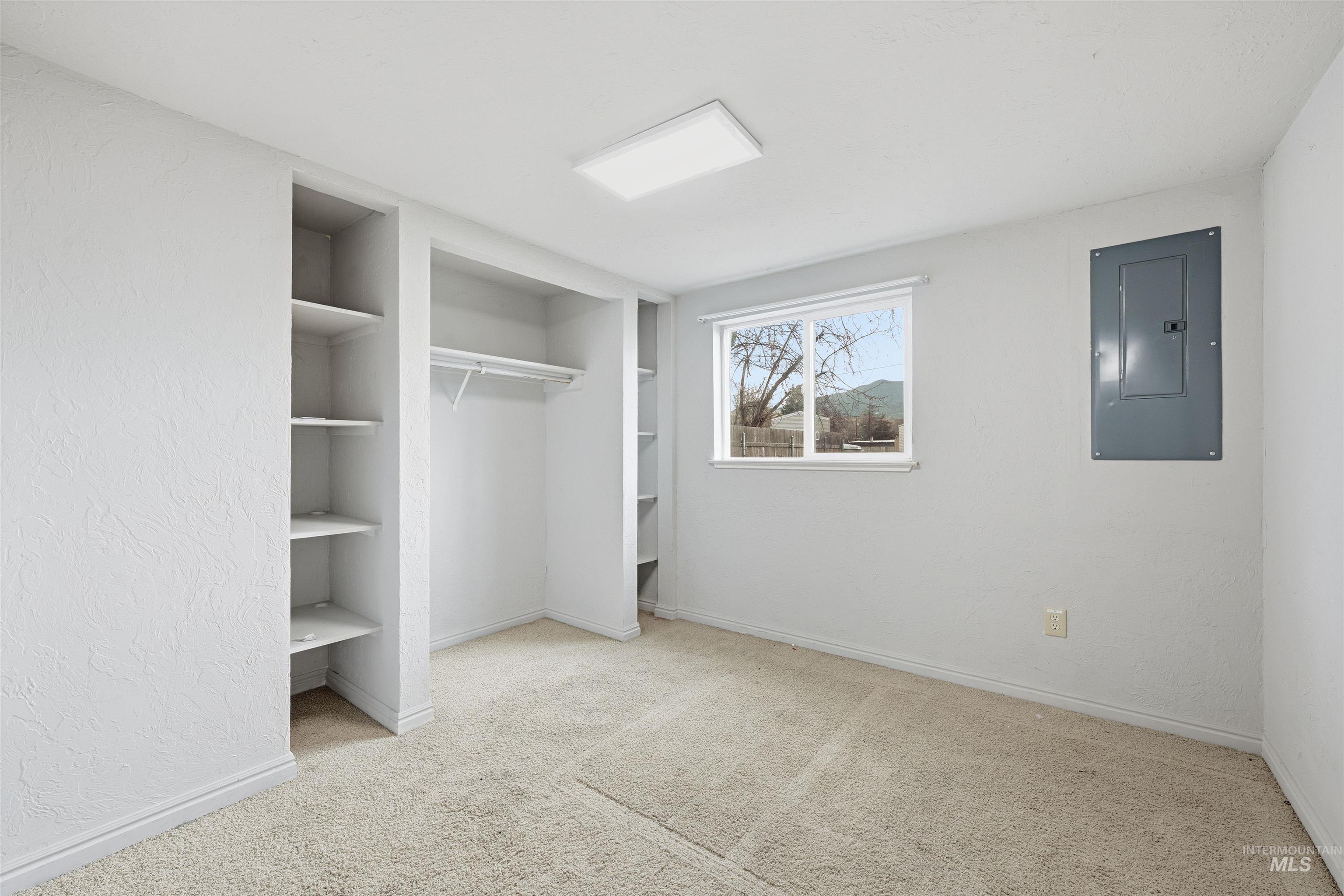 Unfurnished bedroom featuring electric panel, light colored carpet, a closet, and a textured wall