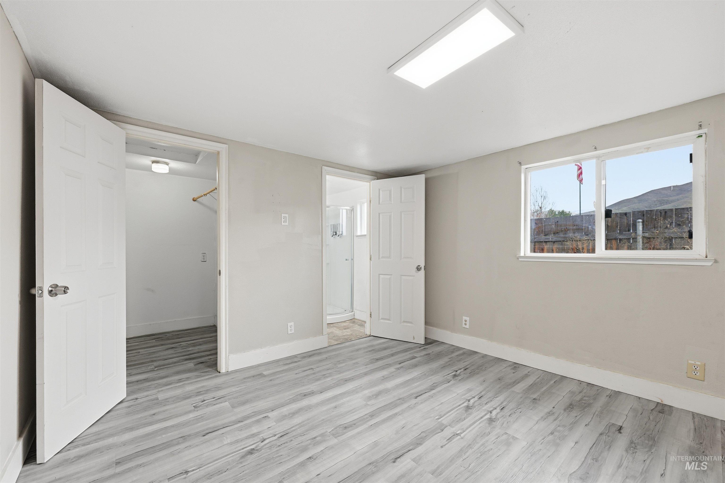 Unfurnished bedroom with a walk in closet and light wood-style flooring