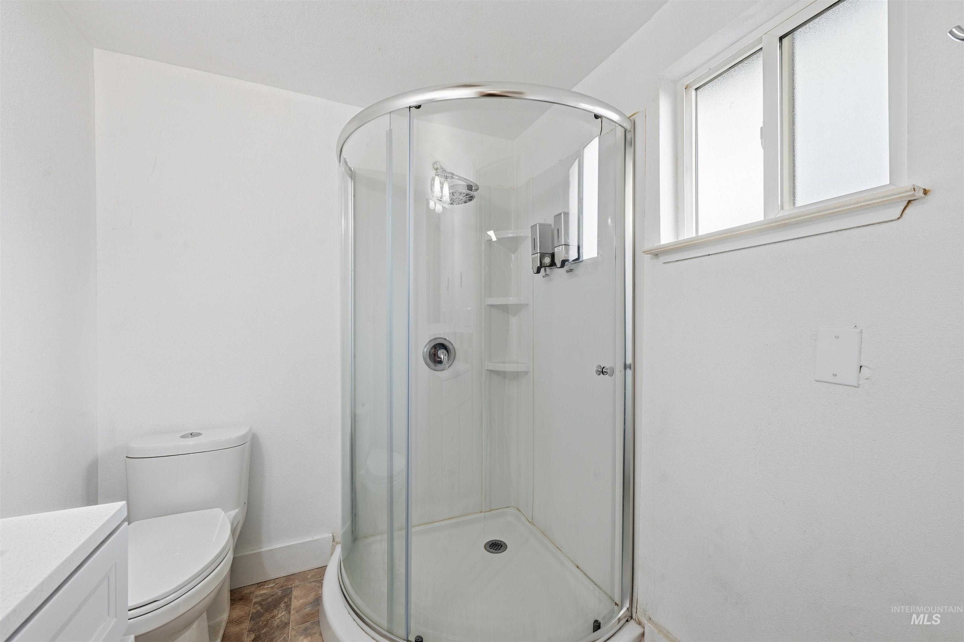 Bathroom featuring a shower stall, vanity, and stone finish floors