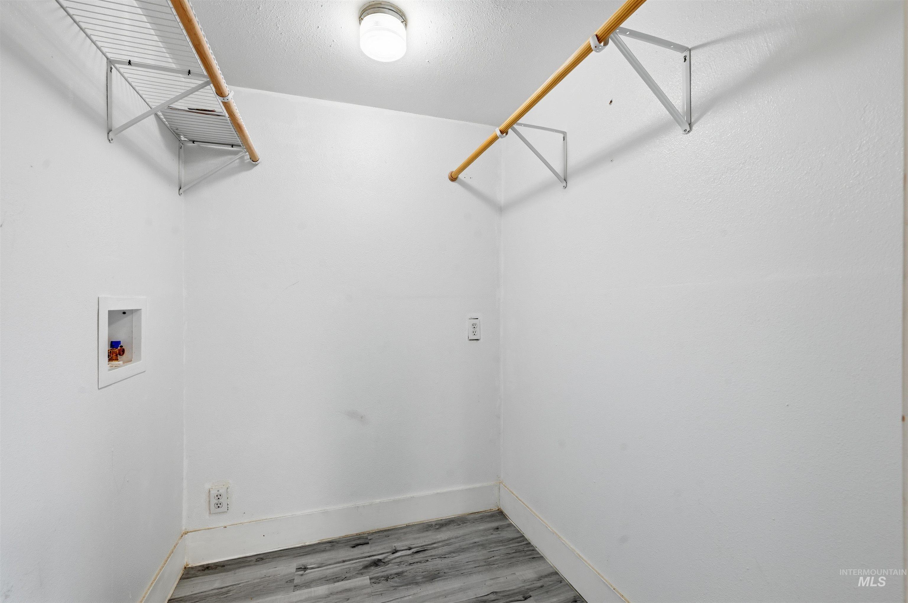 Laundry room with washer hookup, light wood-style floors, and a textured ceiling