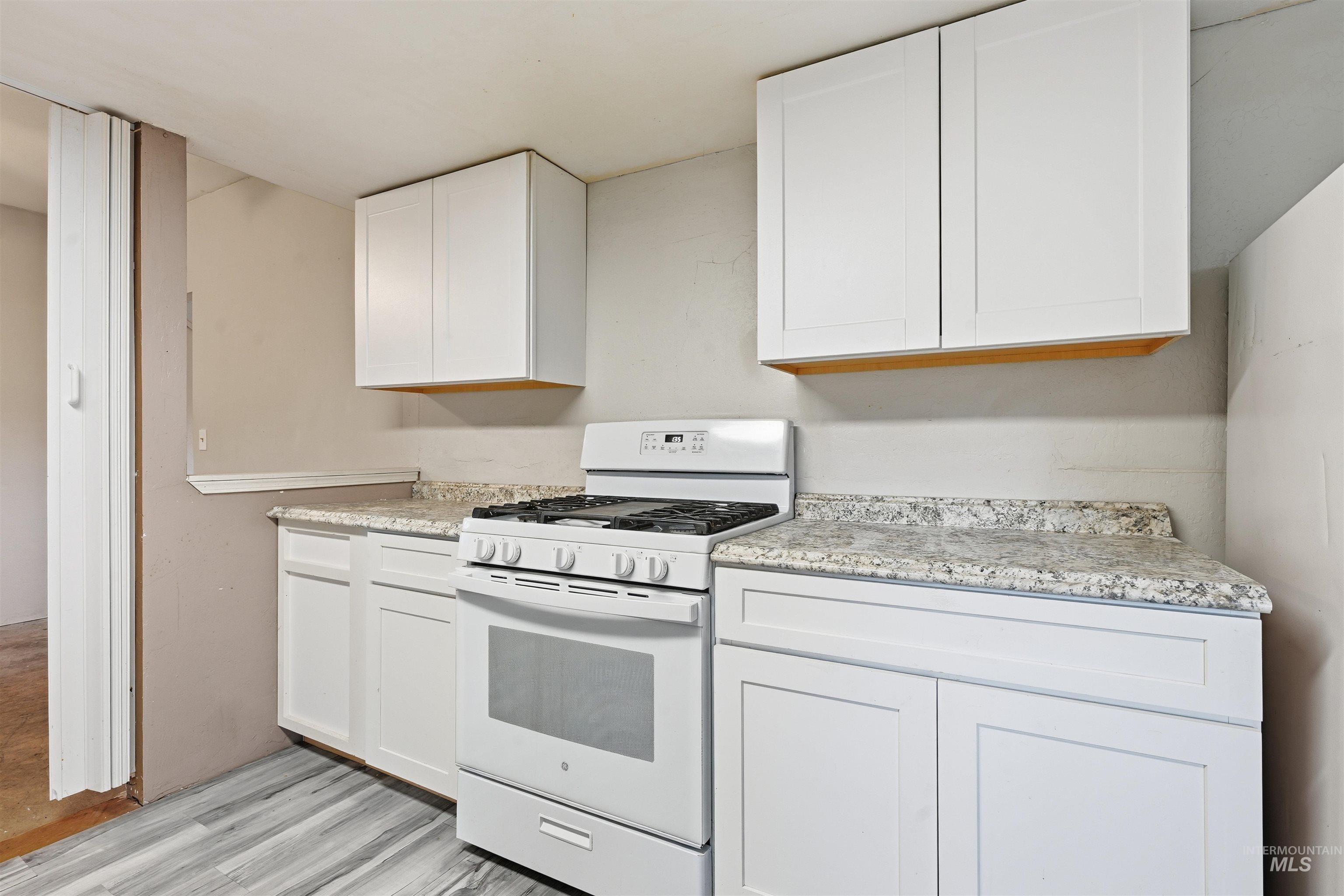 Kitchen featuring gas range gas stove, white cabinetry, and light wood-style flooring
